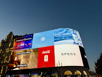Large illuminated billboards on a building at dusk.
