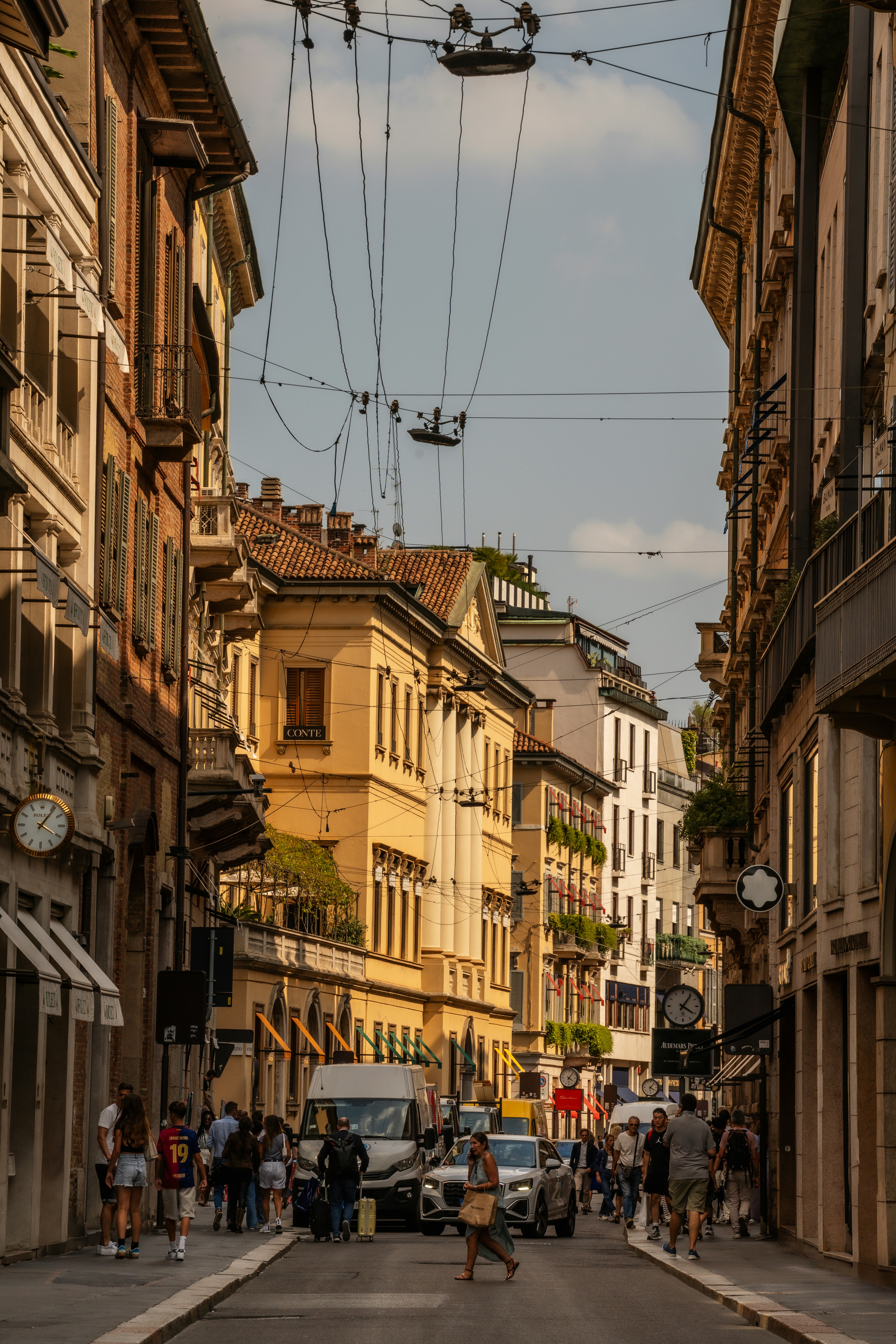 Una calle europea bulliciosa con edificios históricos y cables aéreos.