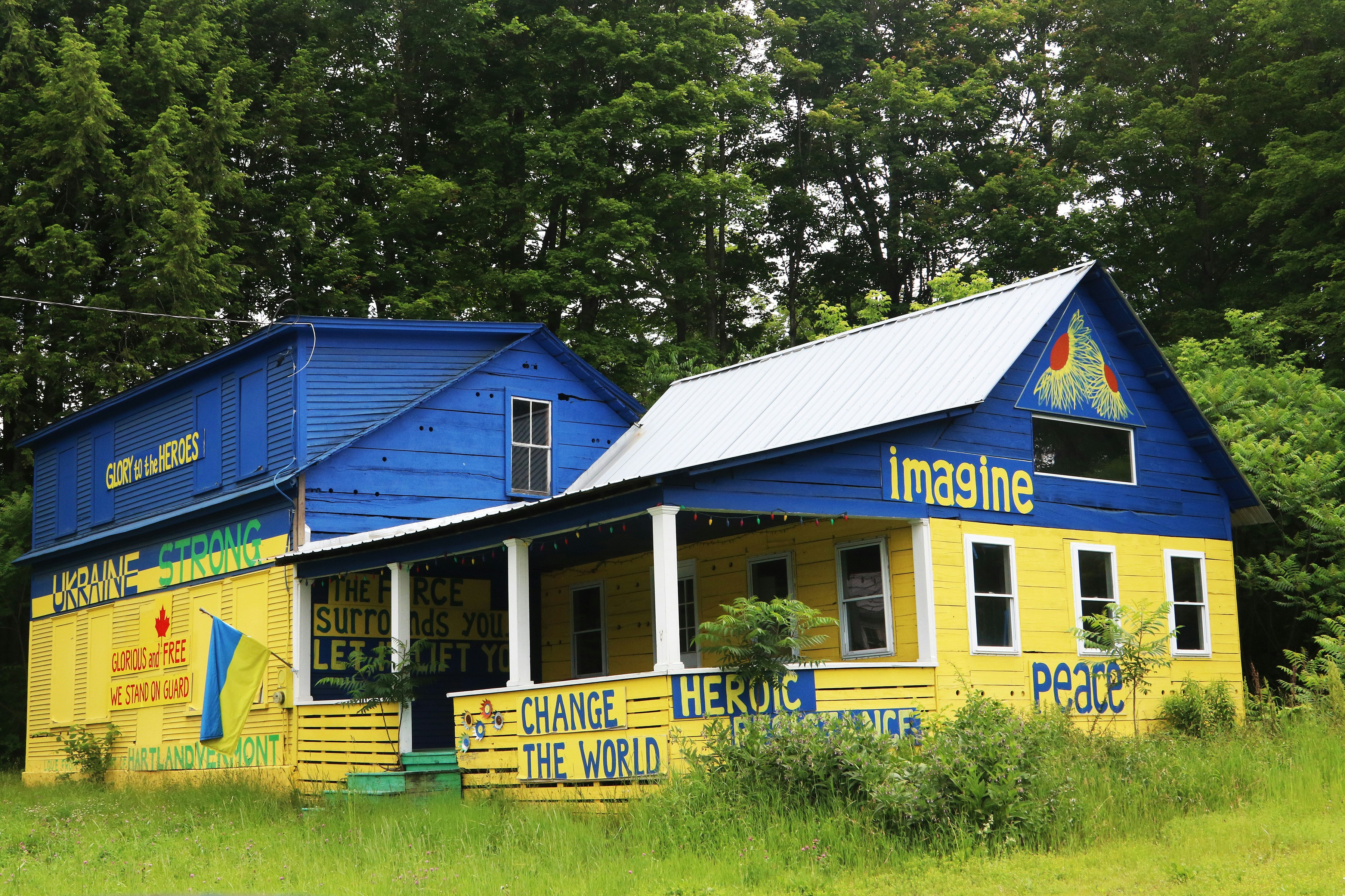 Vibrant blue and yellow house with "imagine" and "peace" signs.