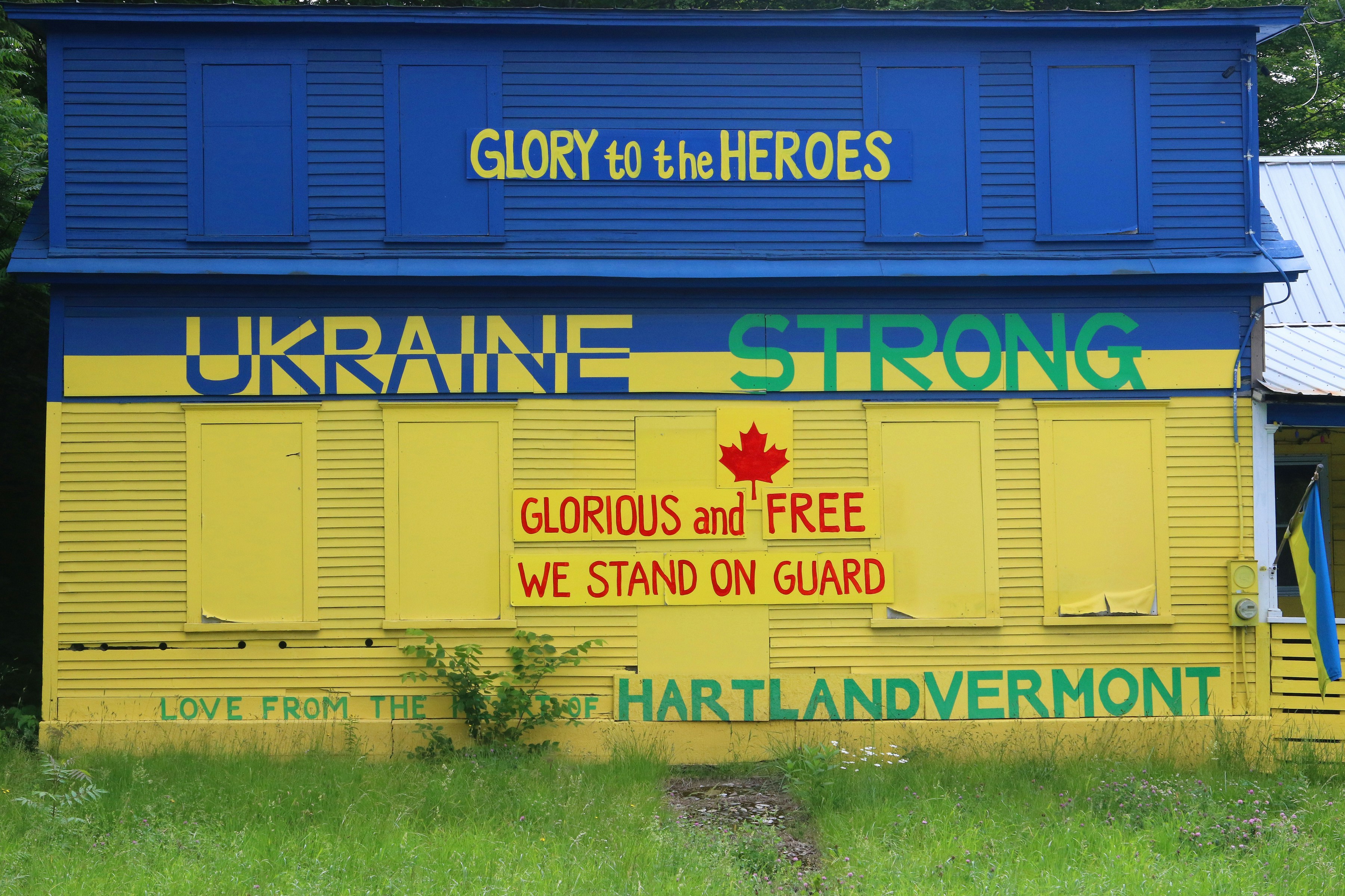 A building painted blue and yellow with messages supporting ukraine.