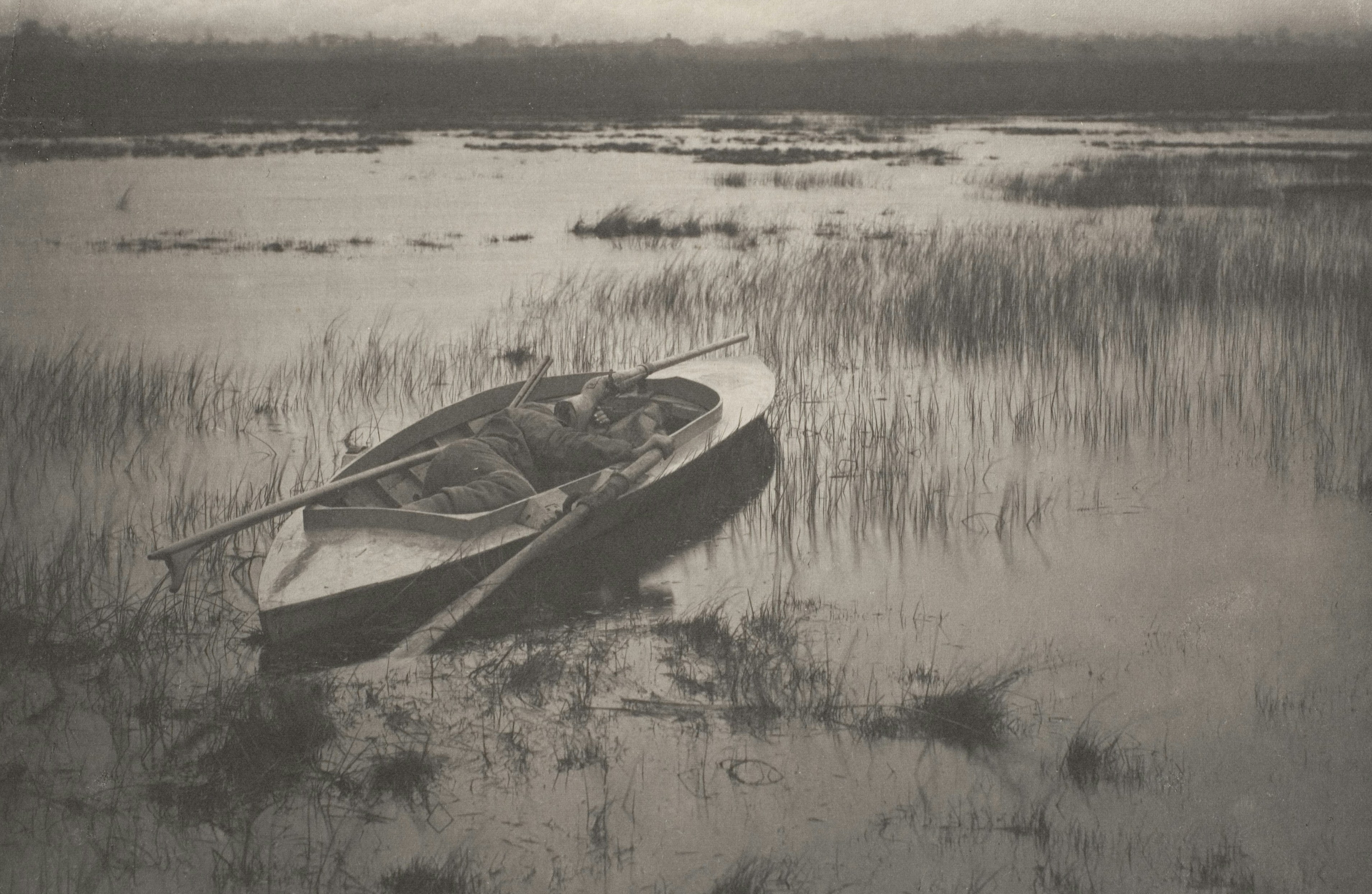 A small boat rests in a misty, grassy marsh.