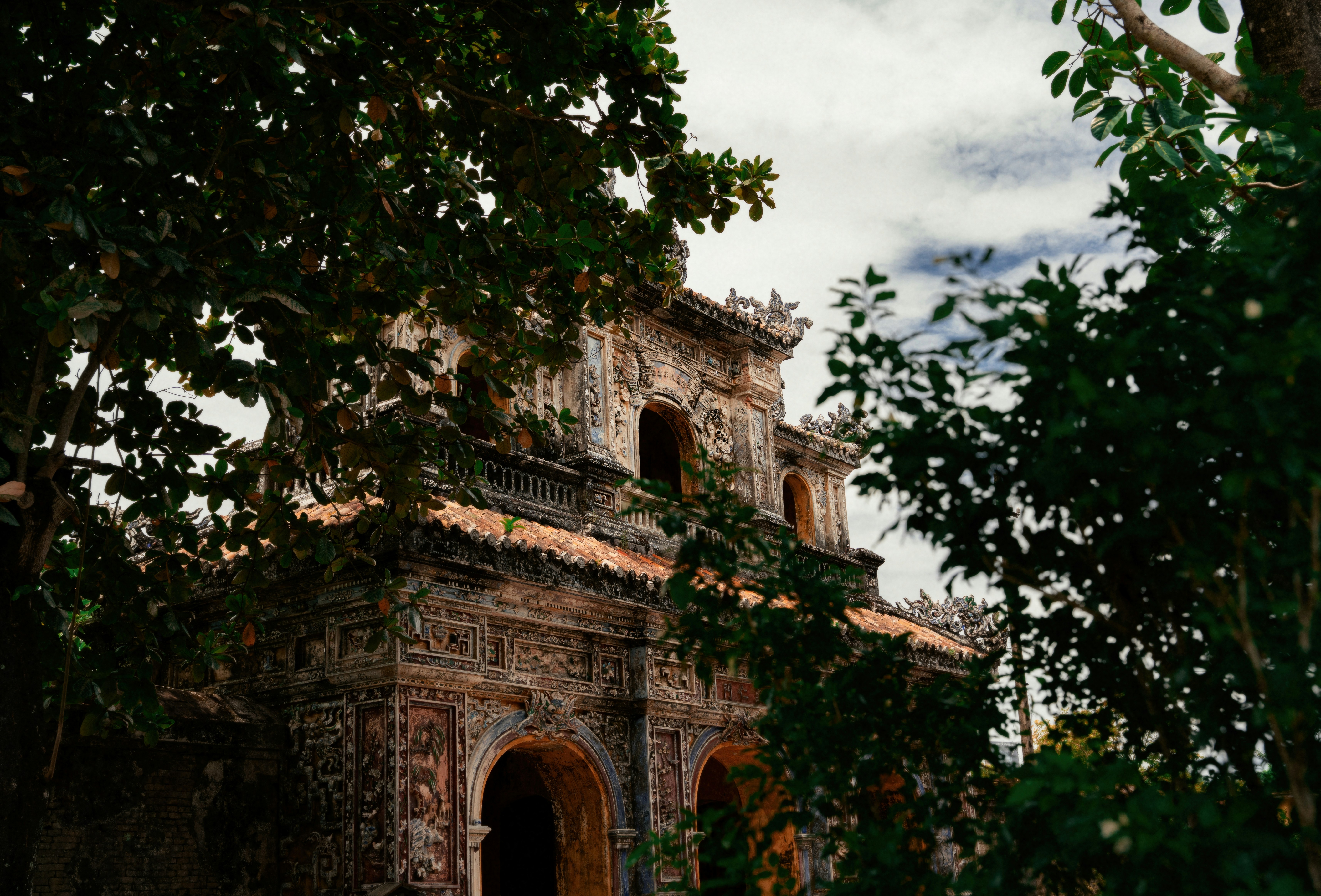 An ornate gate of the Hue Imperial Citadel framed by trees
