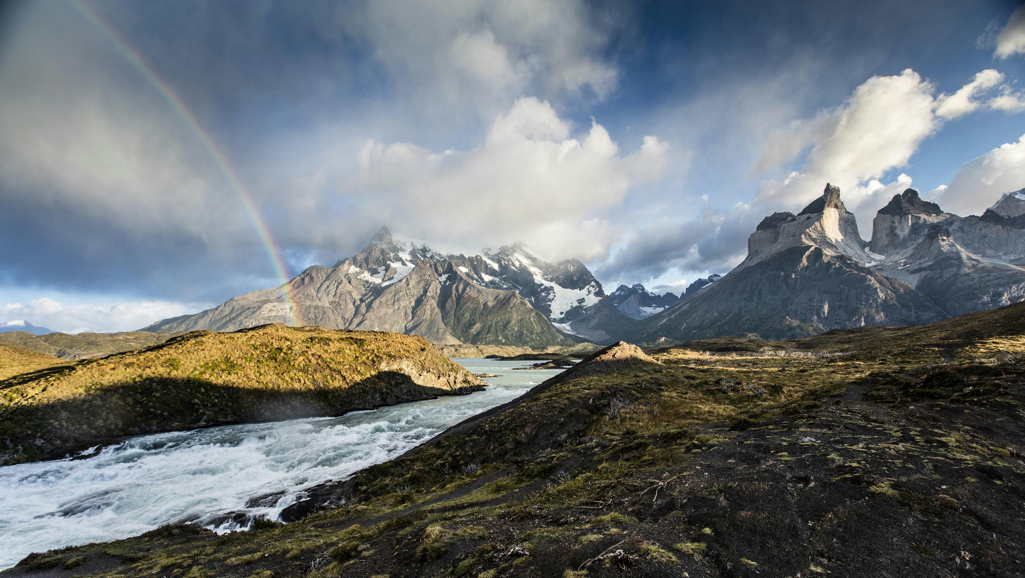 Rainbow arches over torres del paine mountains and river