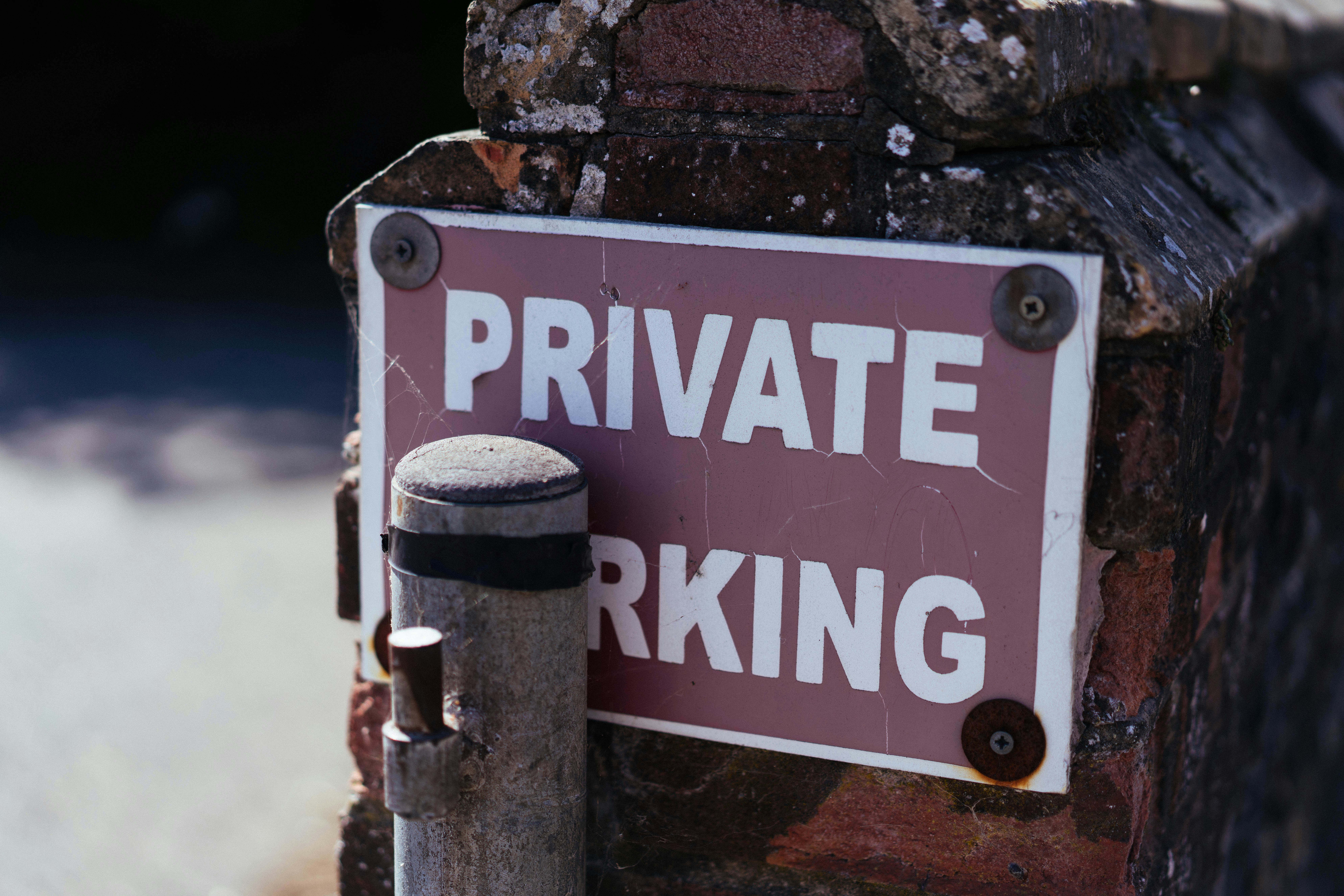 A "private parking" sign is attached to a brick pillar.