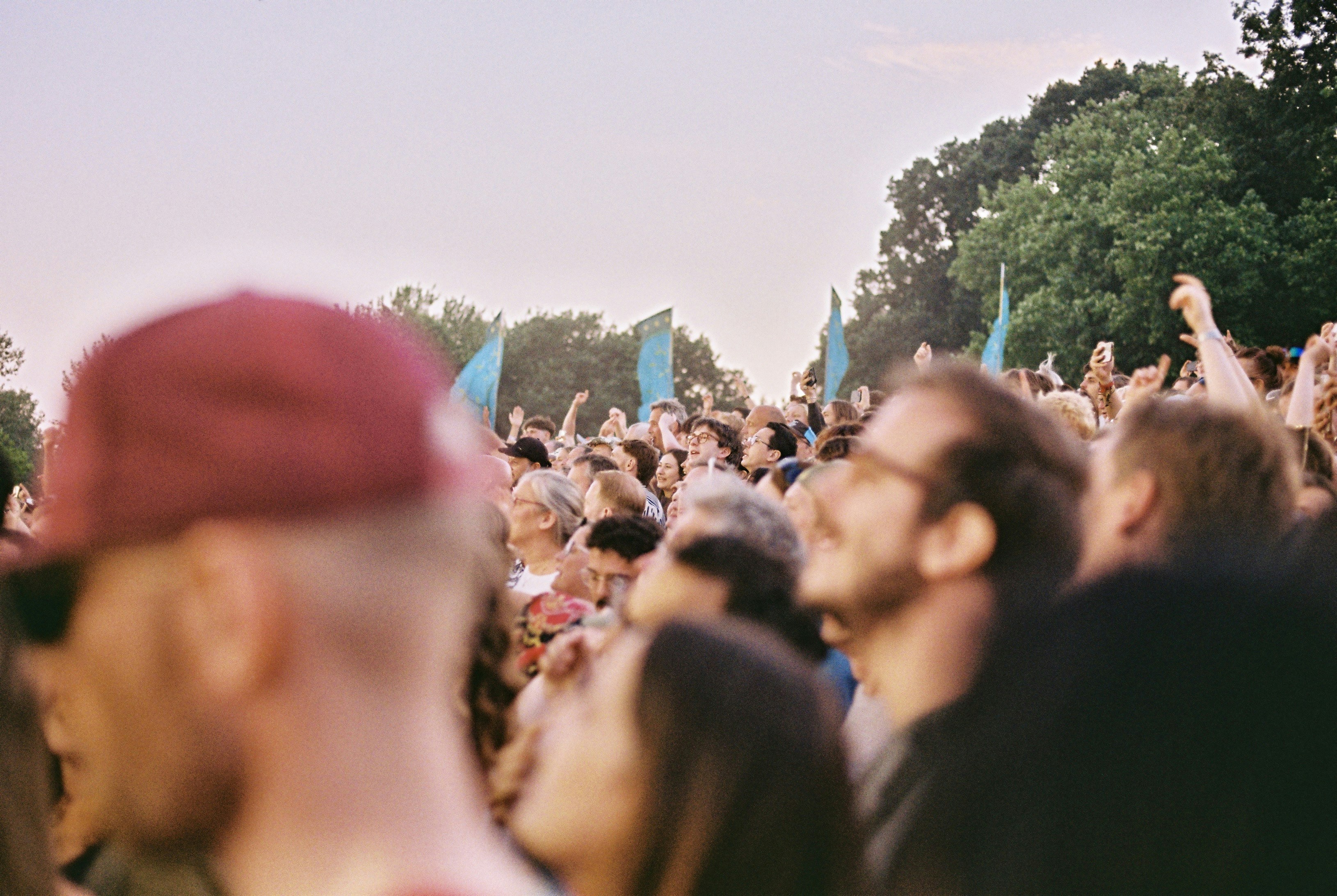 Festival crowd looking up under teal flags at golden hour