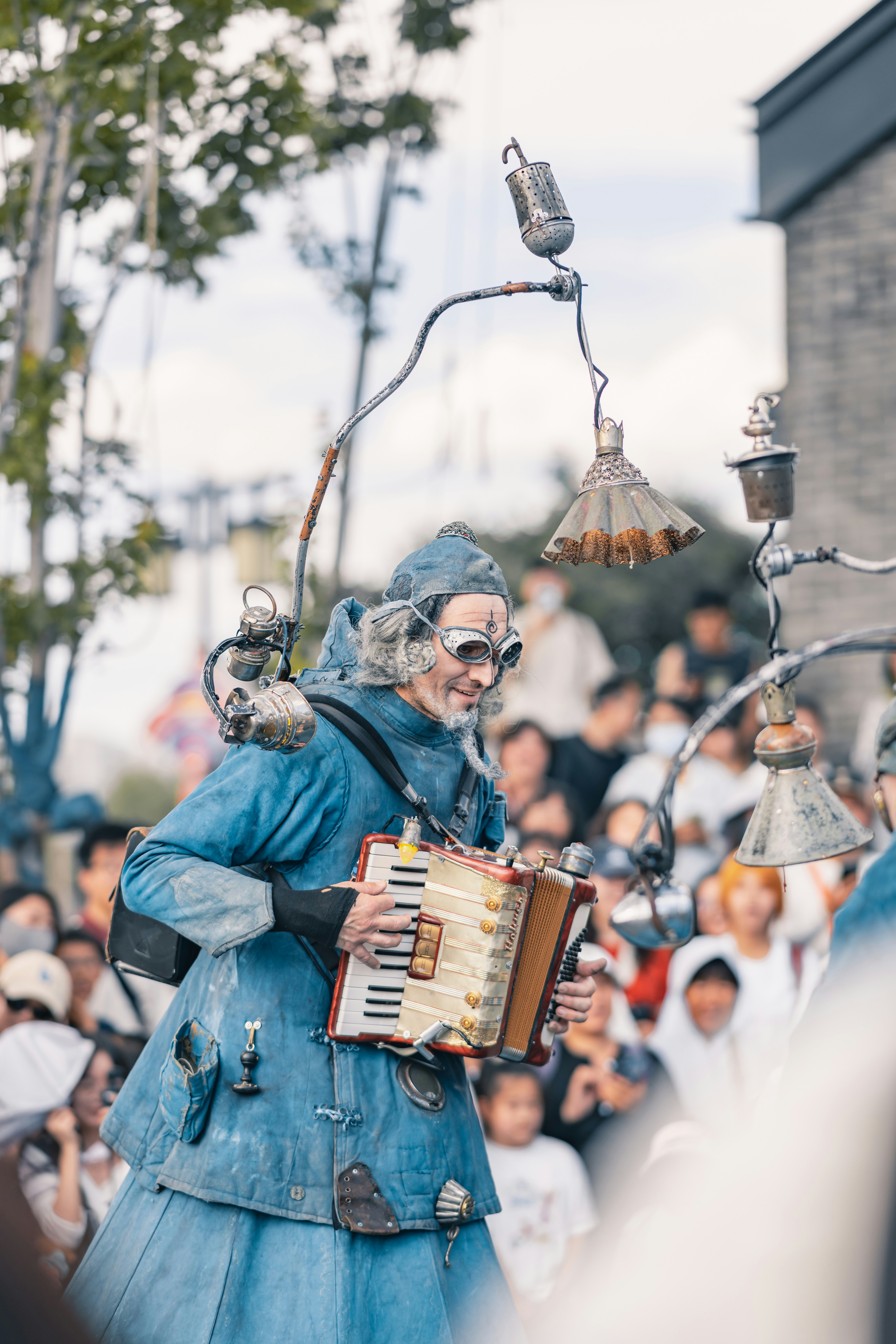 Artista callejero con traje azul y lámparas tocando el acordeón.
