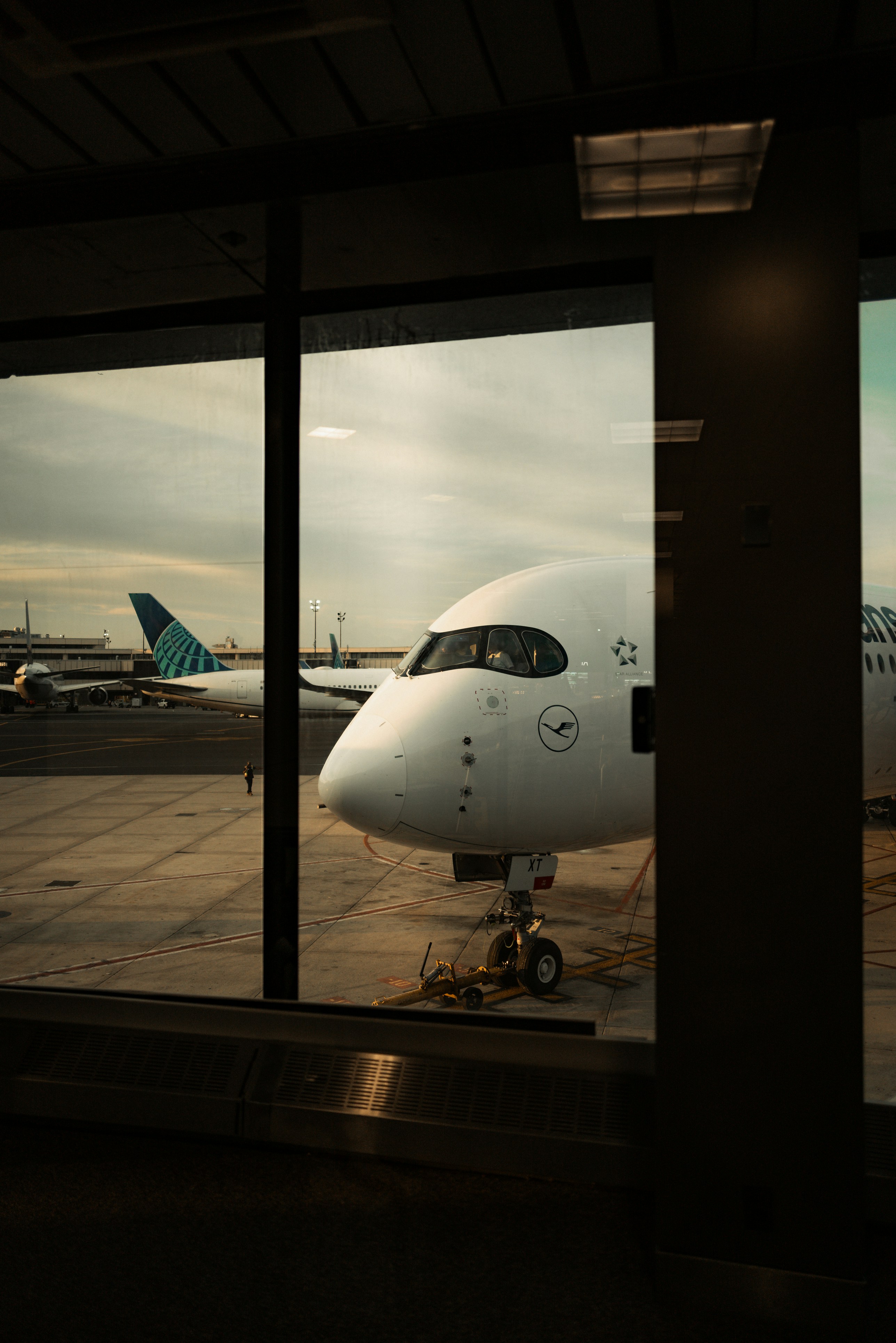 White airplane parked on tarmac viewed through a window