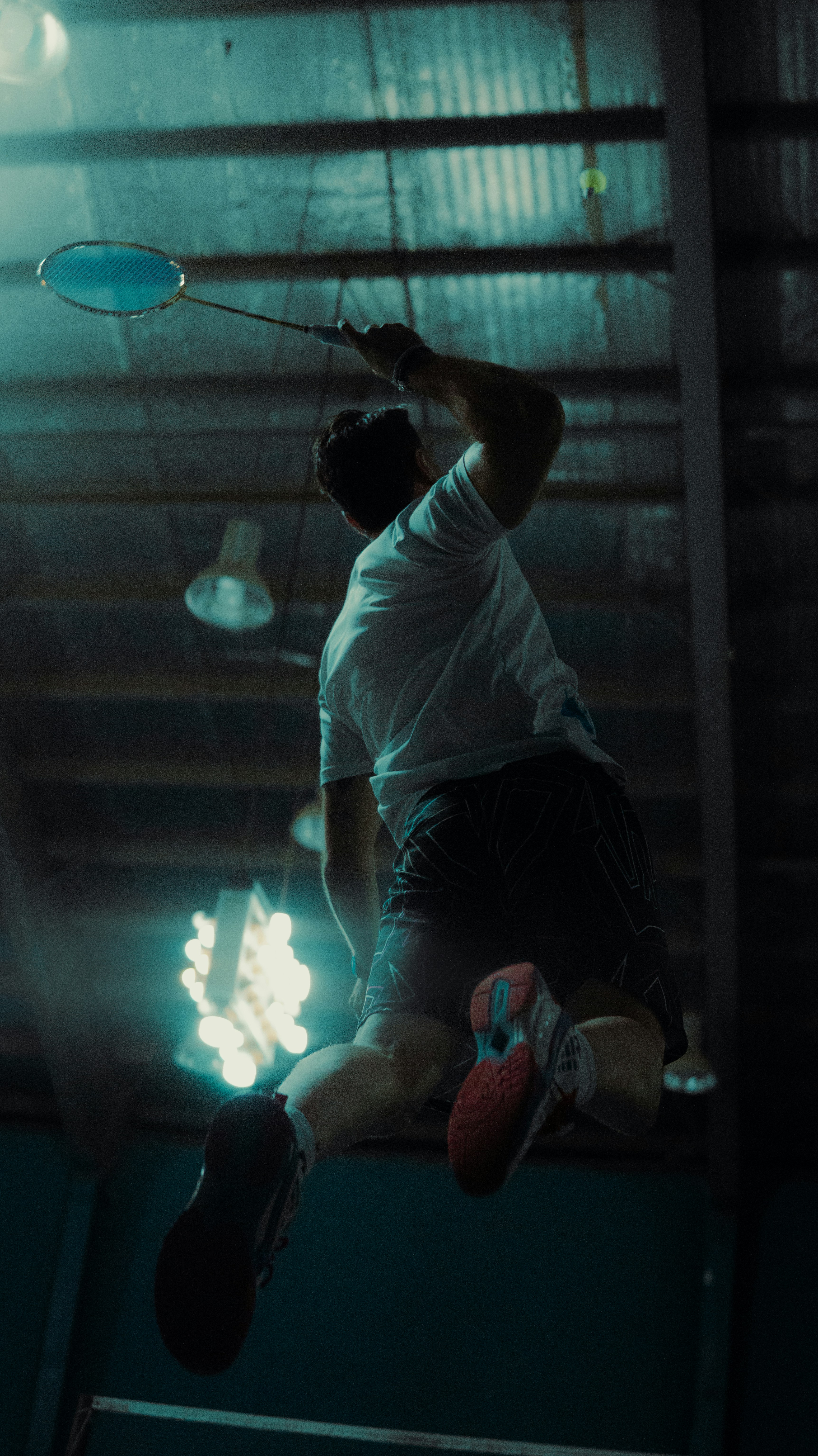 Badminton player in mid-air hitting a shuttlecock