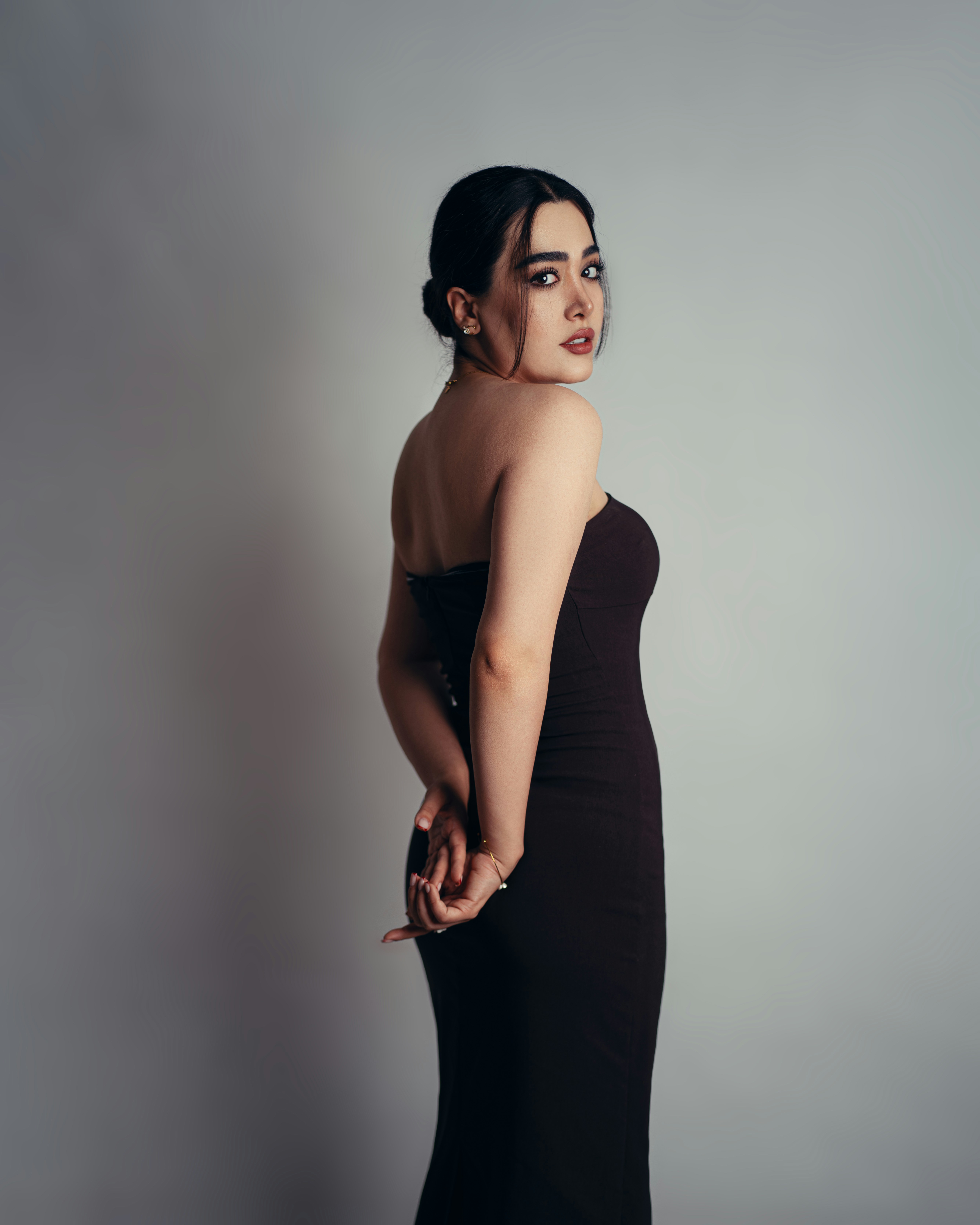 A woman in a strapless black dress looking back