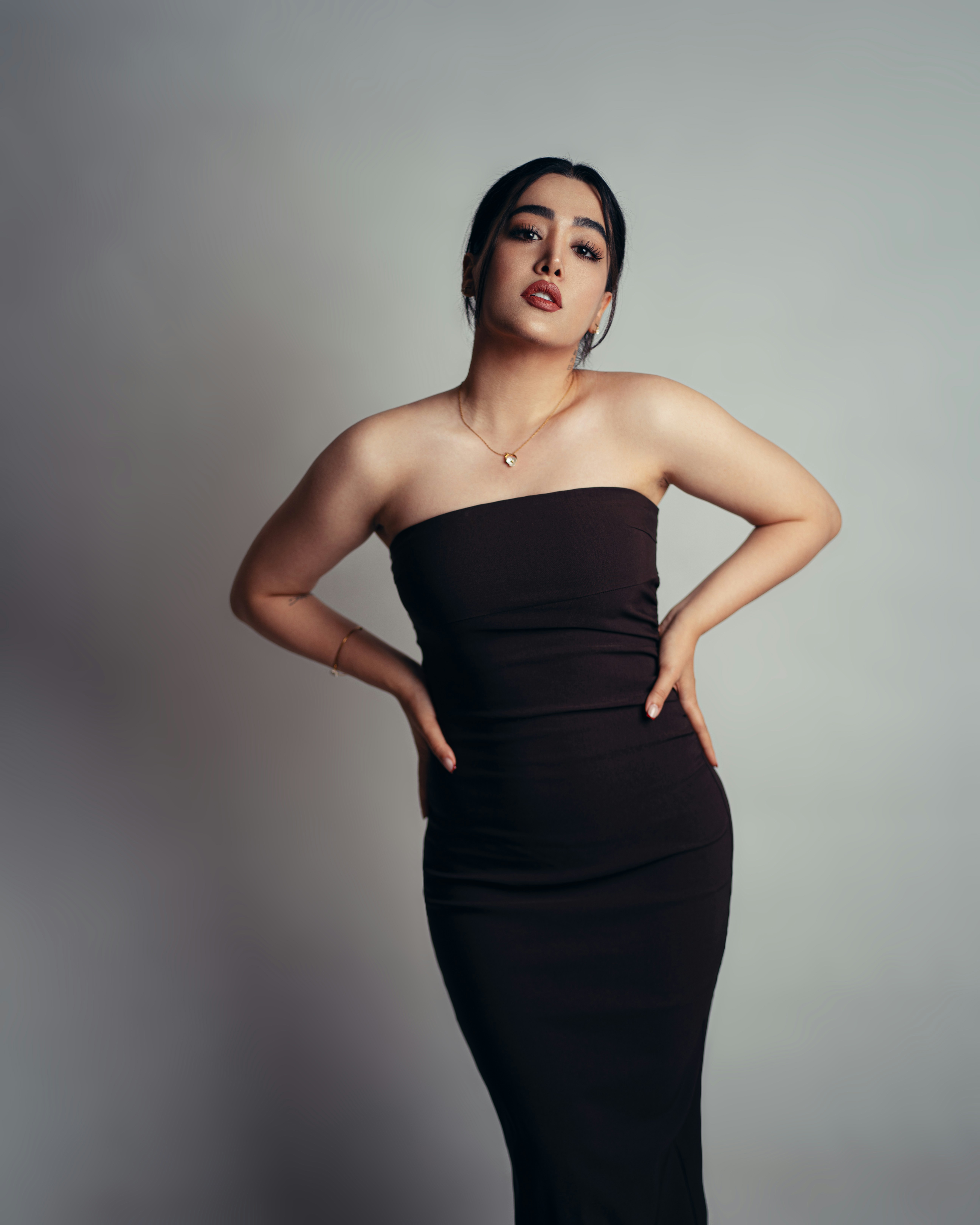 Woman in a black strapless dress wearing a delicate necklace and bracelet