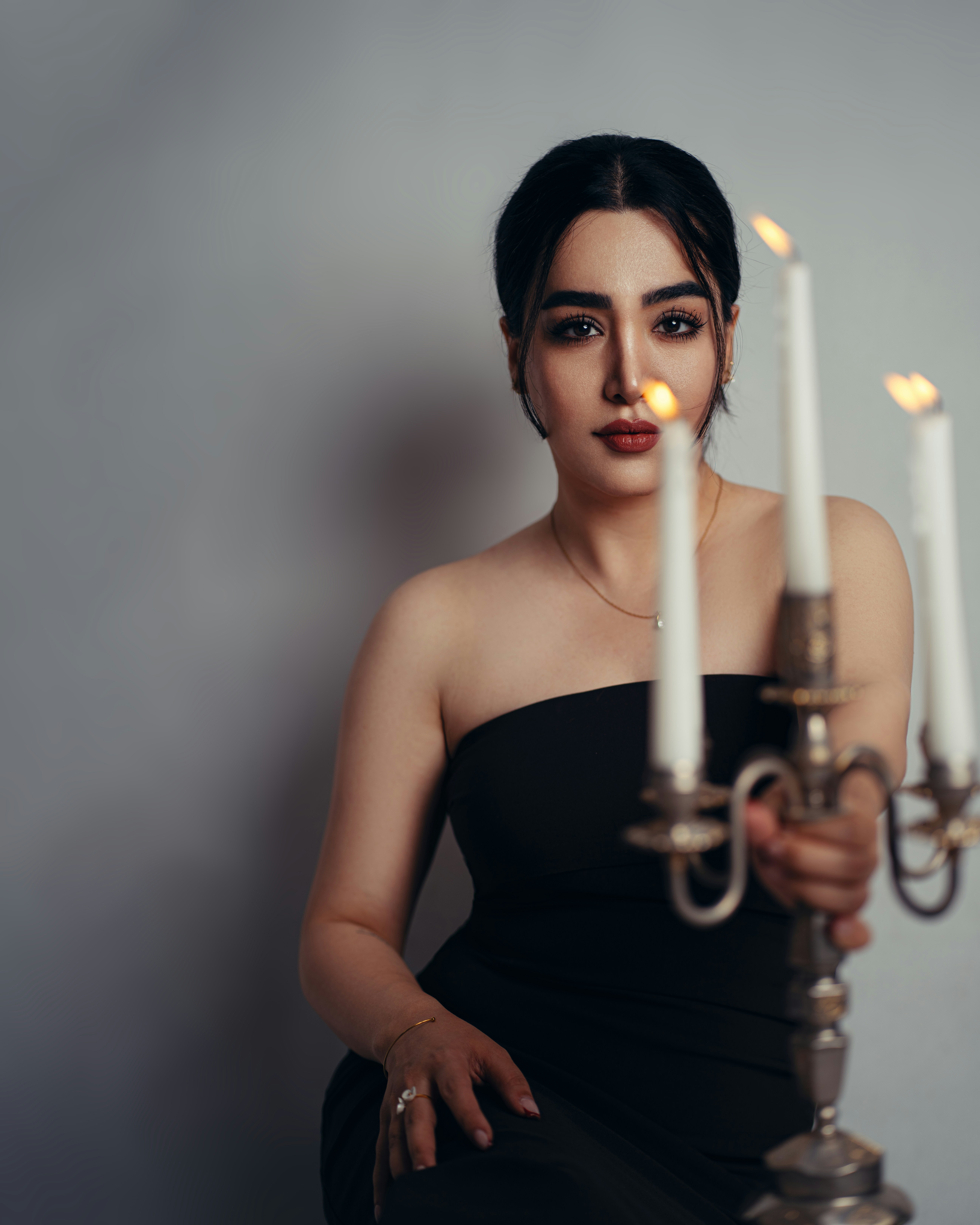 A woman in a black dress holding a lit candelabra