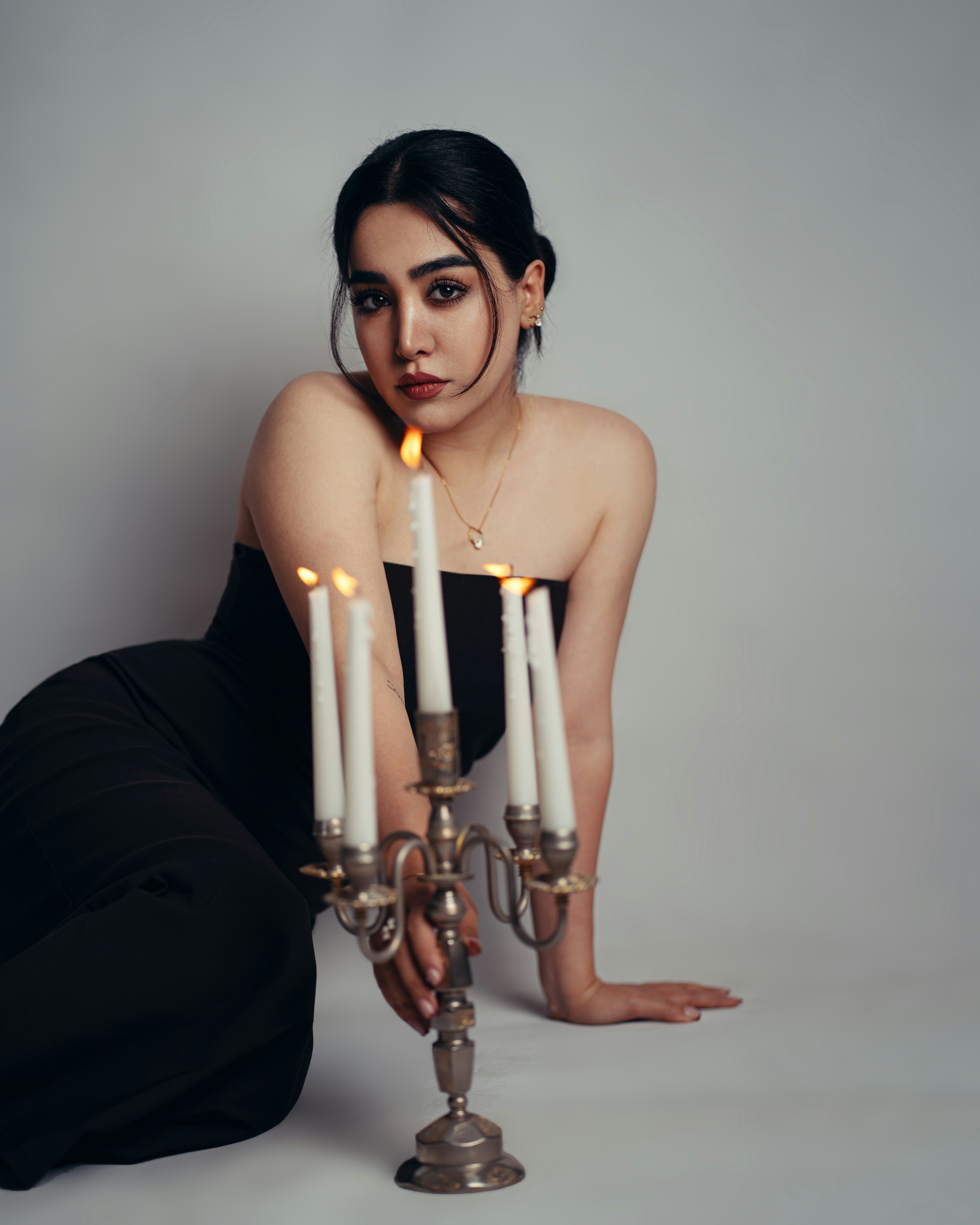 Young woman in black sitting with a lit candelabra