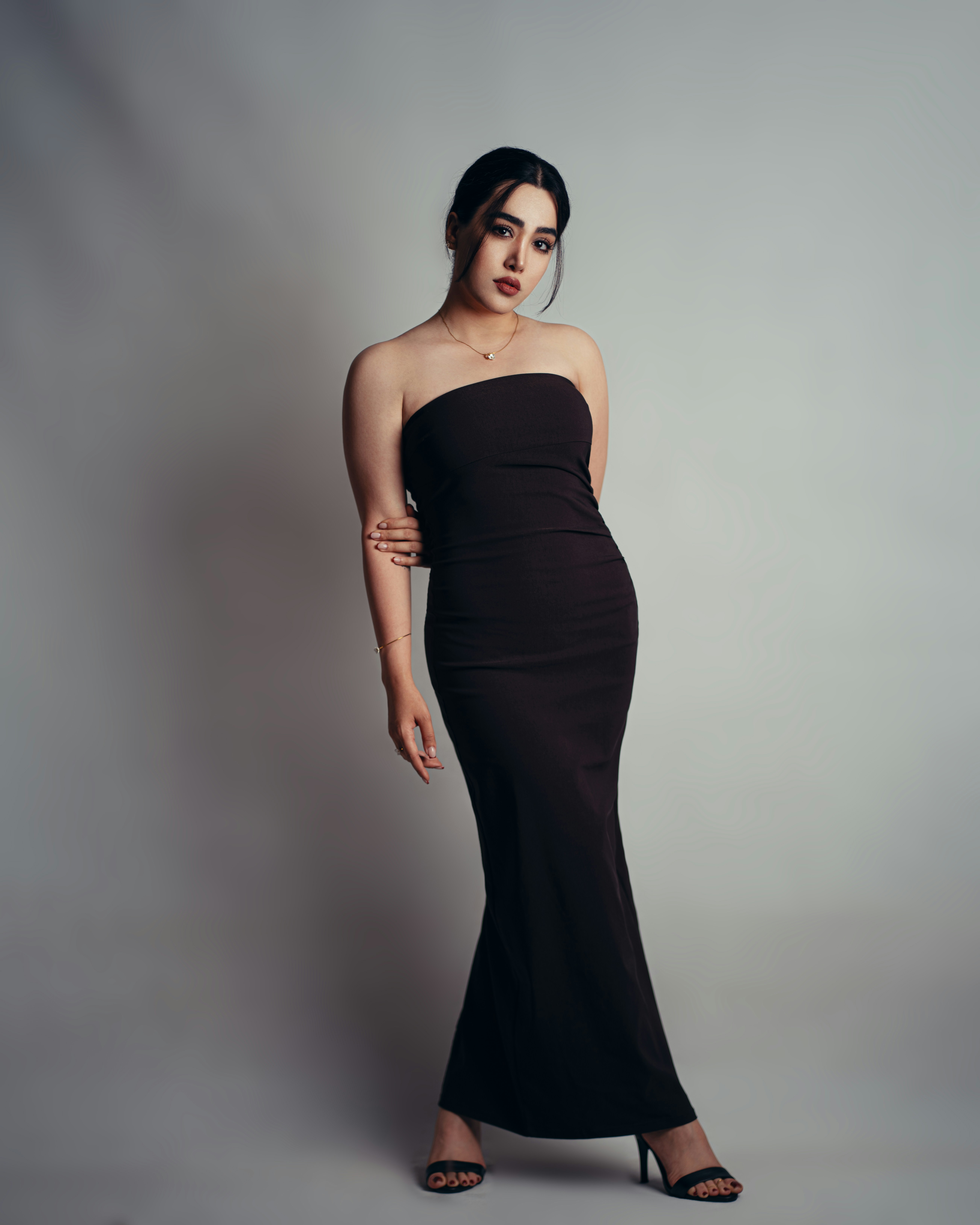 Woman posing in a long black strapless dress