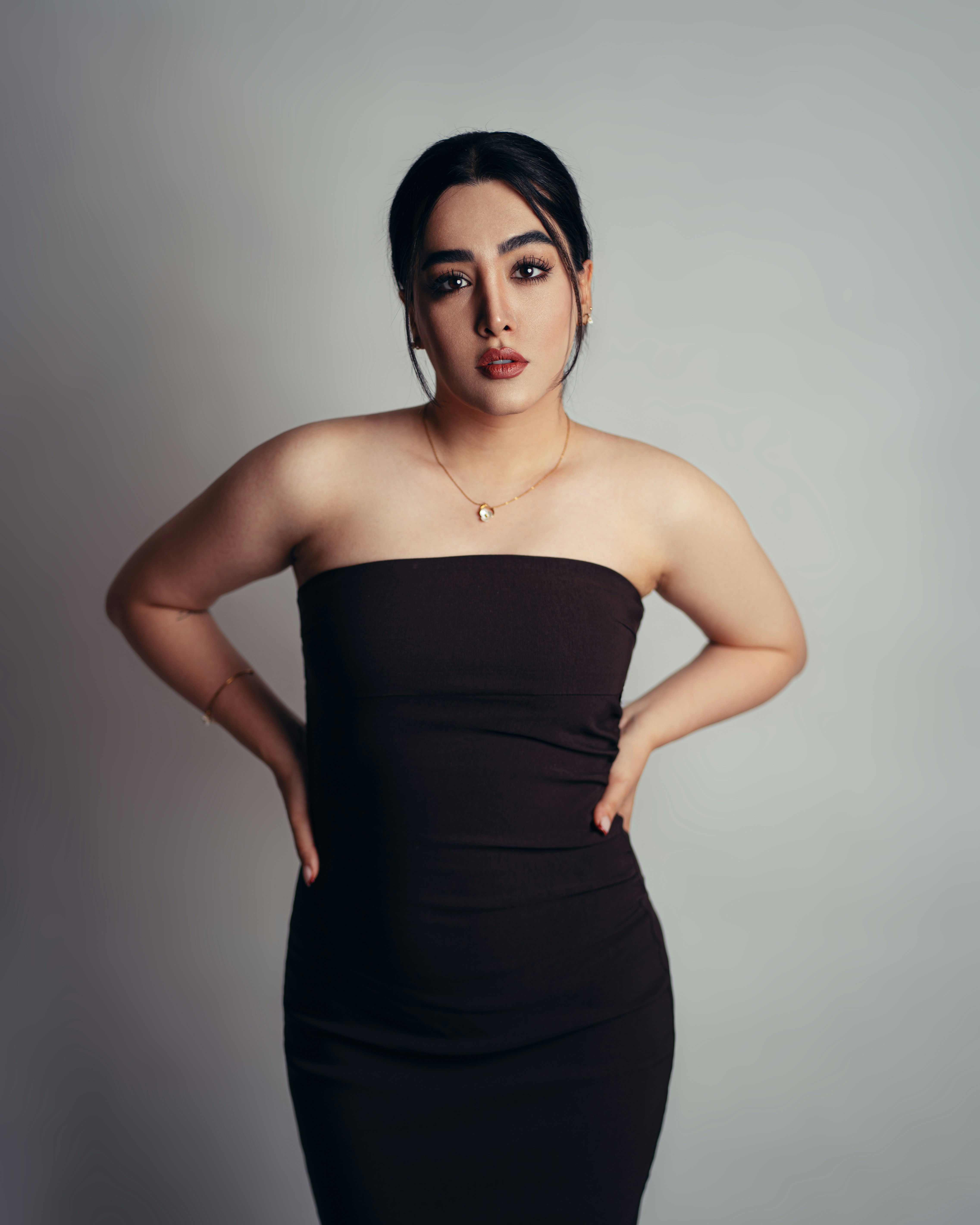 A young woman in a black strapless dress posing