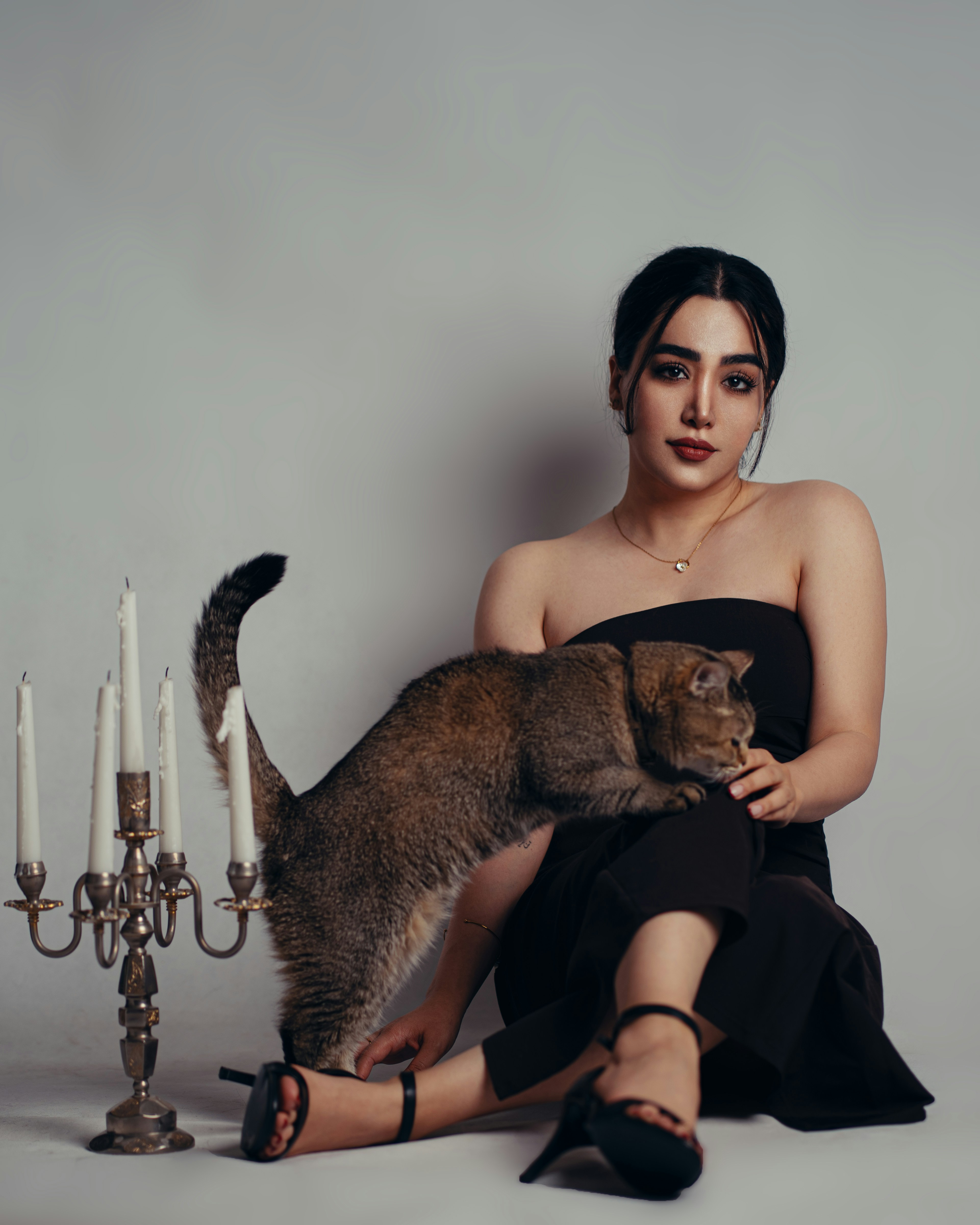Elegant woman in black with a cat and candelabra
