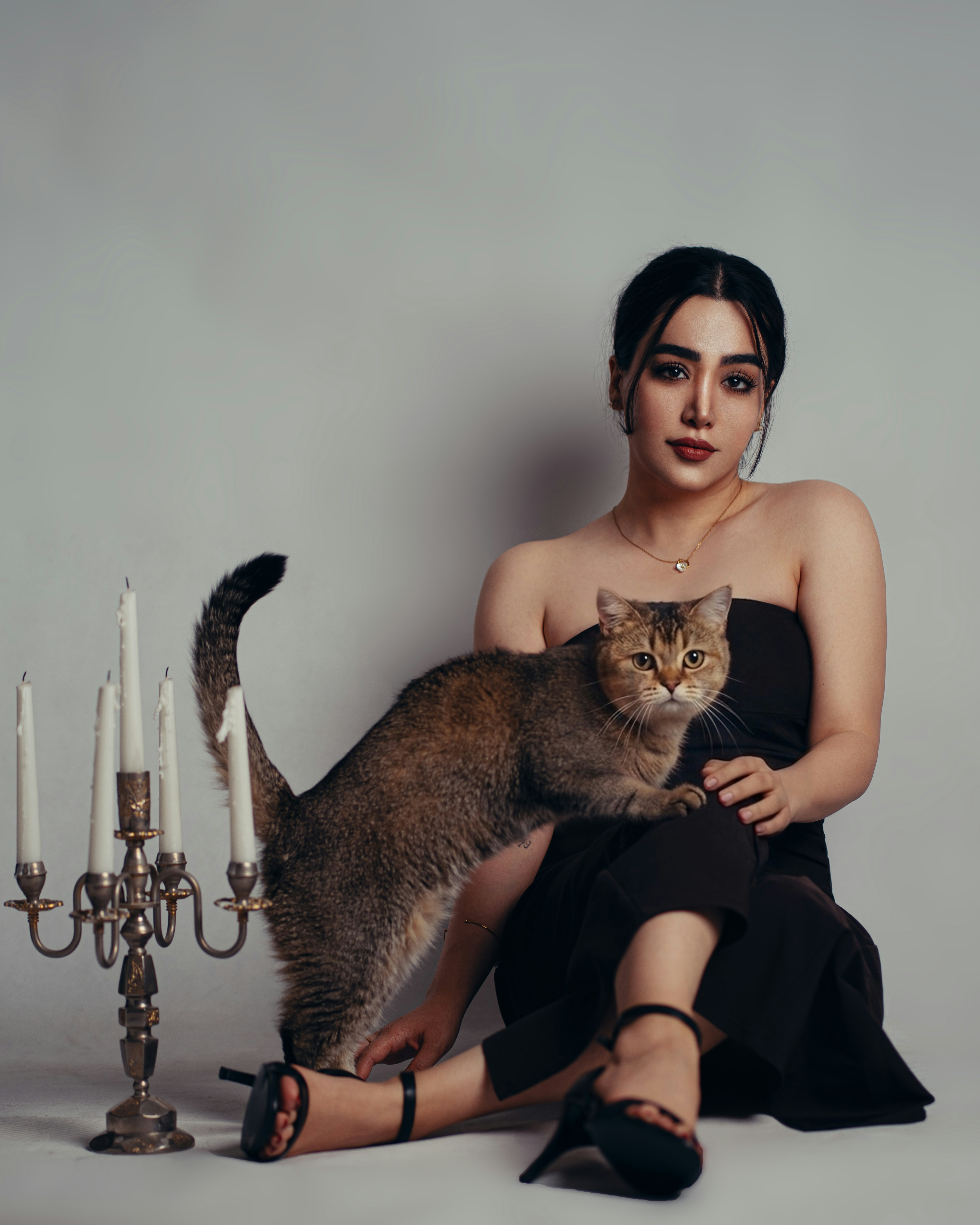 A woman and a cat posing elegantly with a candelabra