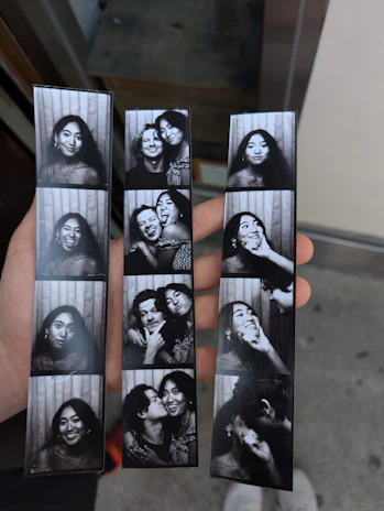 Hand holding three black and white photo booth strips