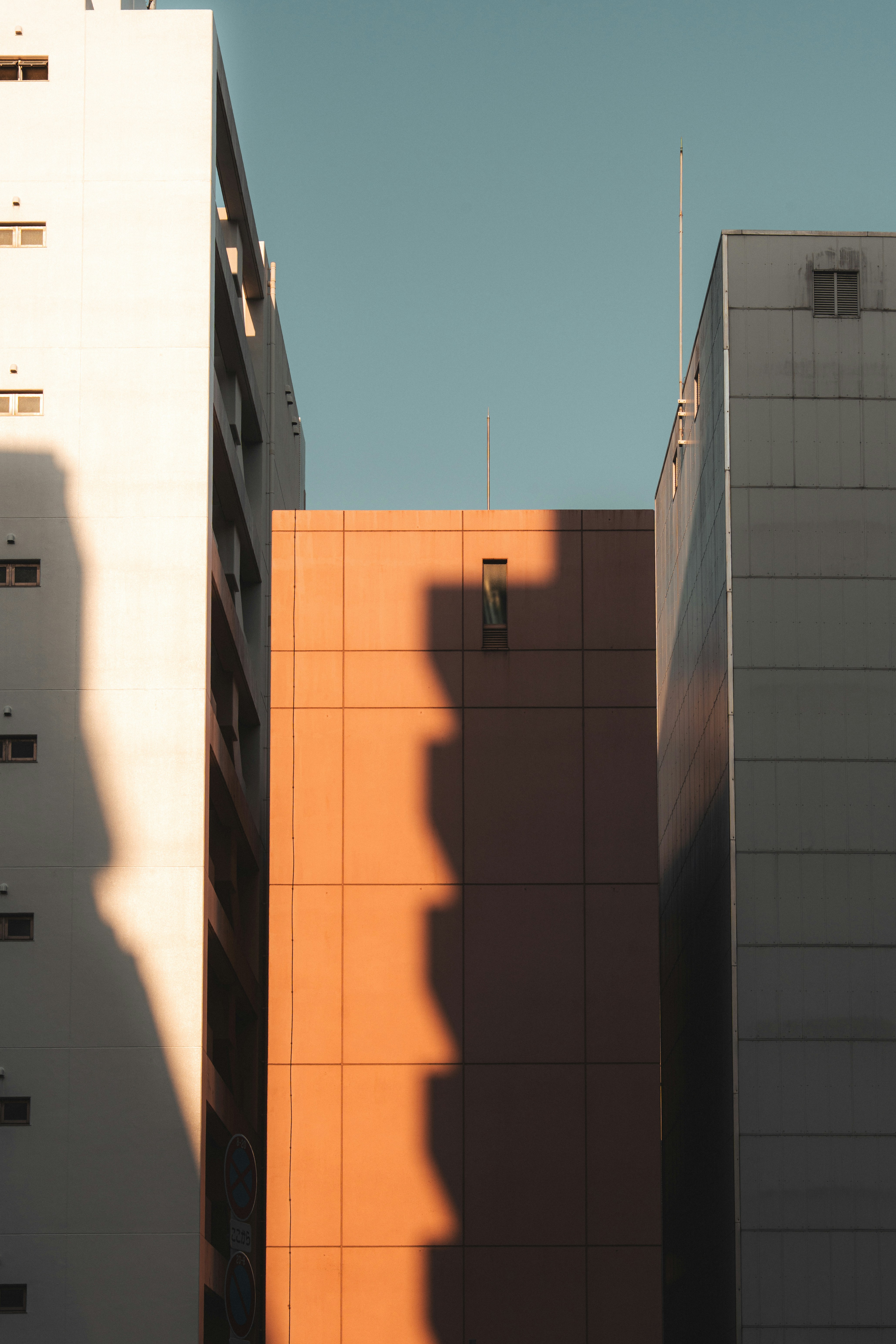 Tall buildings with strong shadows under a clear blue sky.