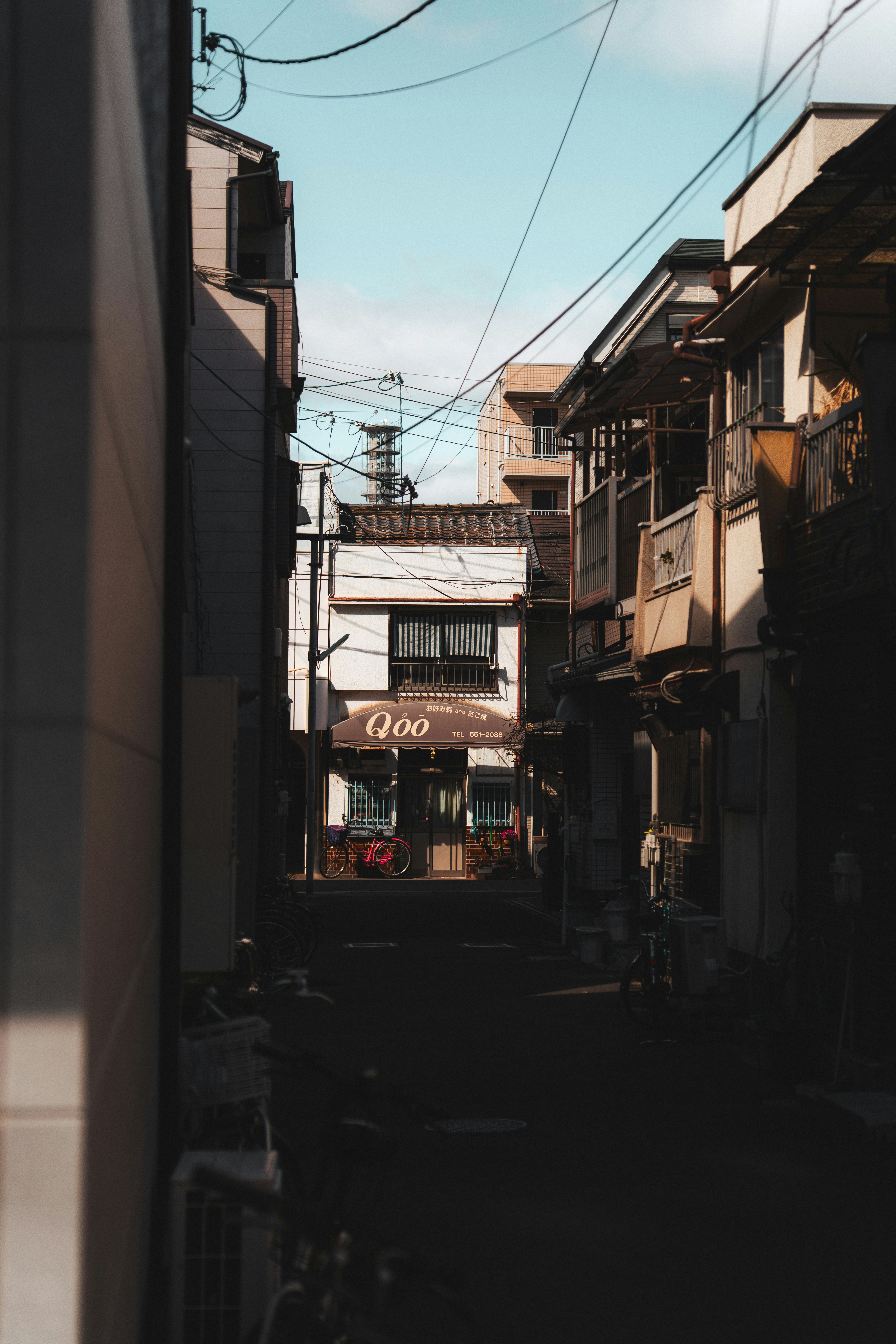 Narrow urban alleyway with buildings and overhead power lines.