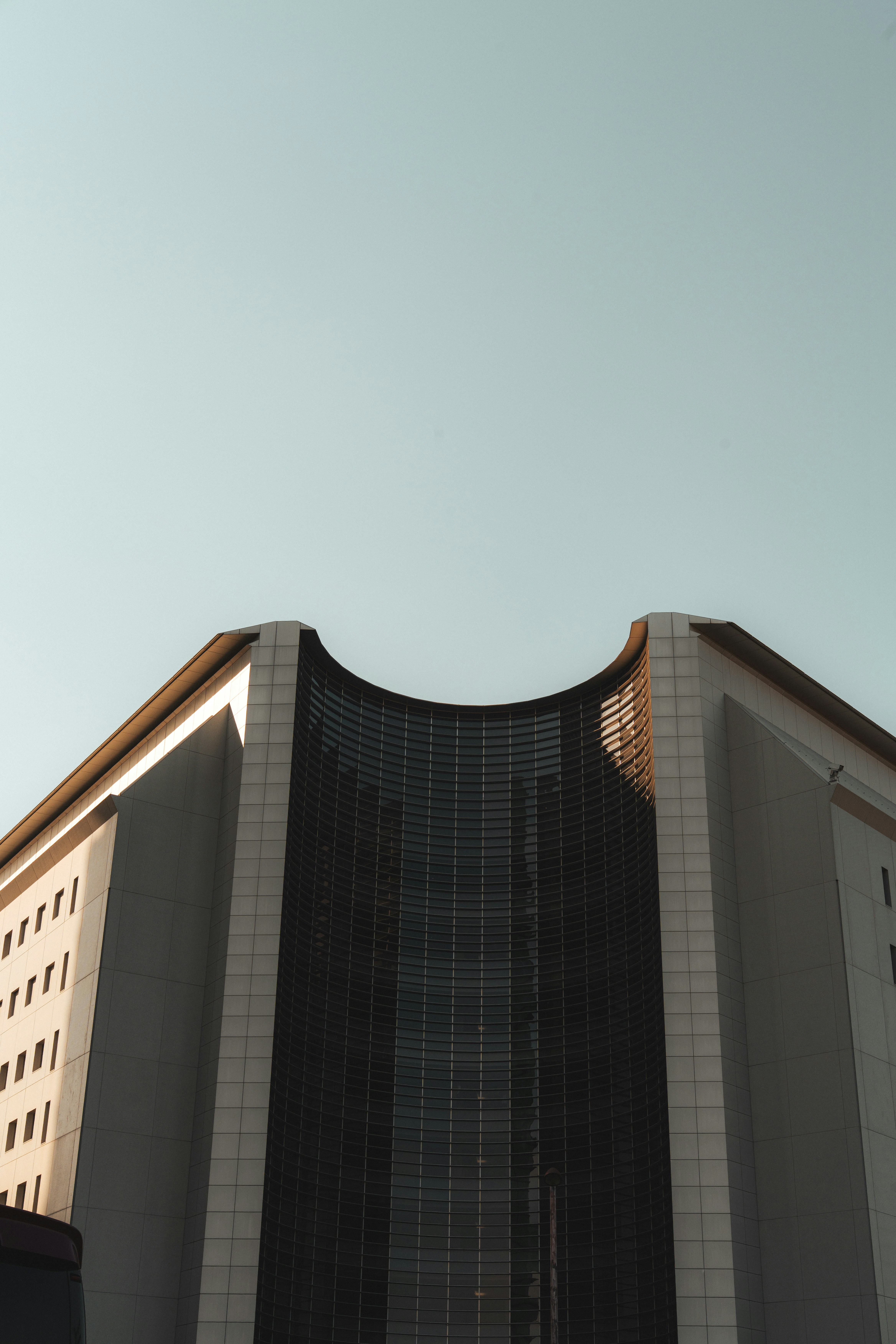 Modern building with curved glass facade against a clear sky.