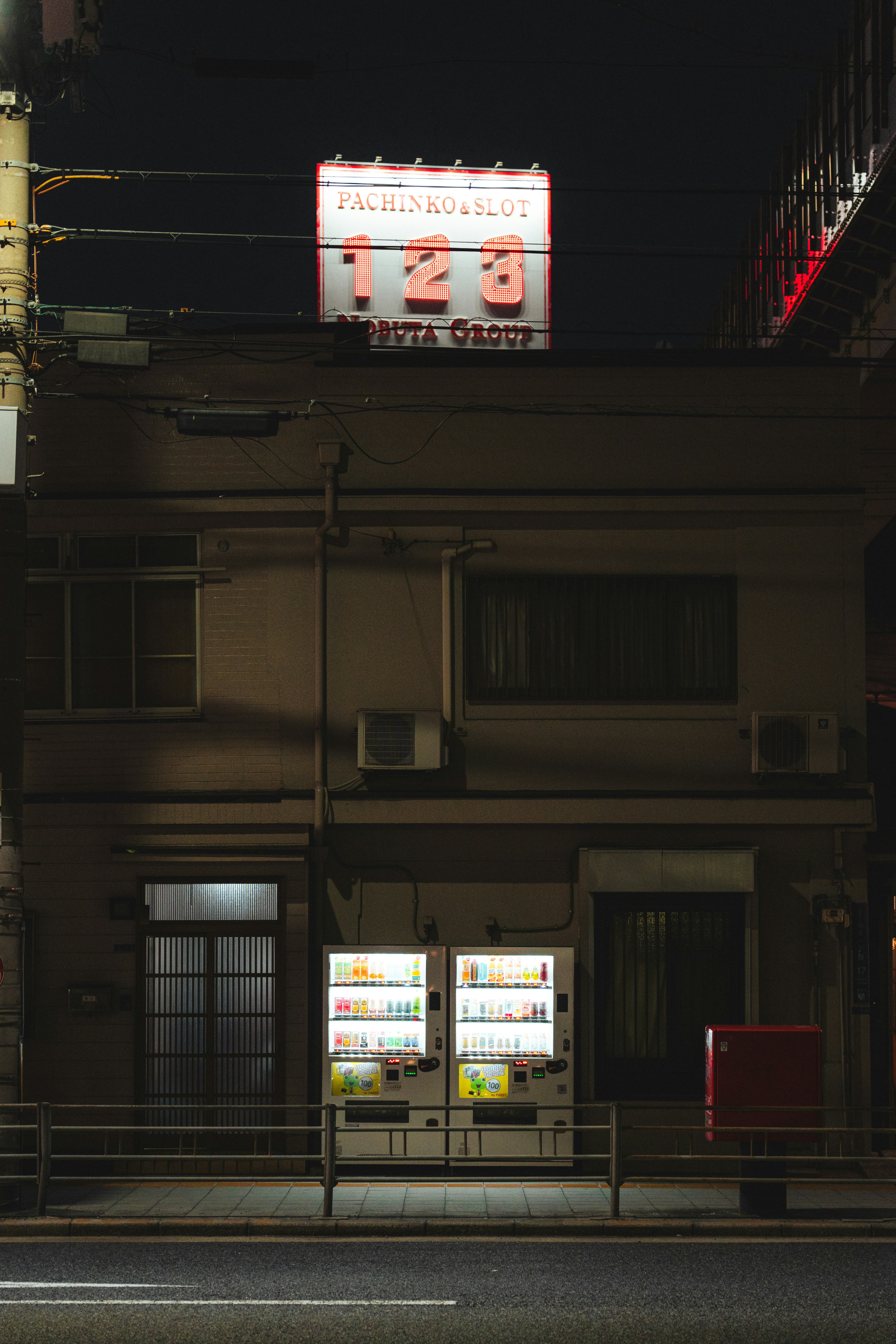 Vending machines and glowing sign on building at night.