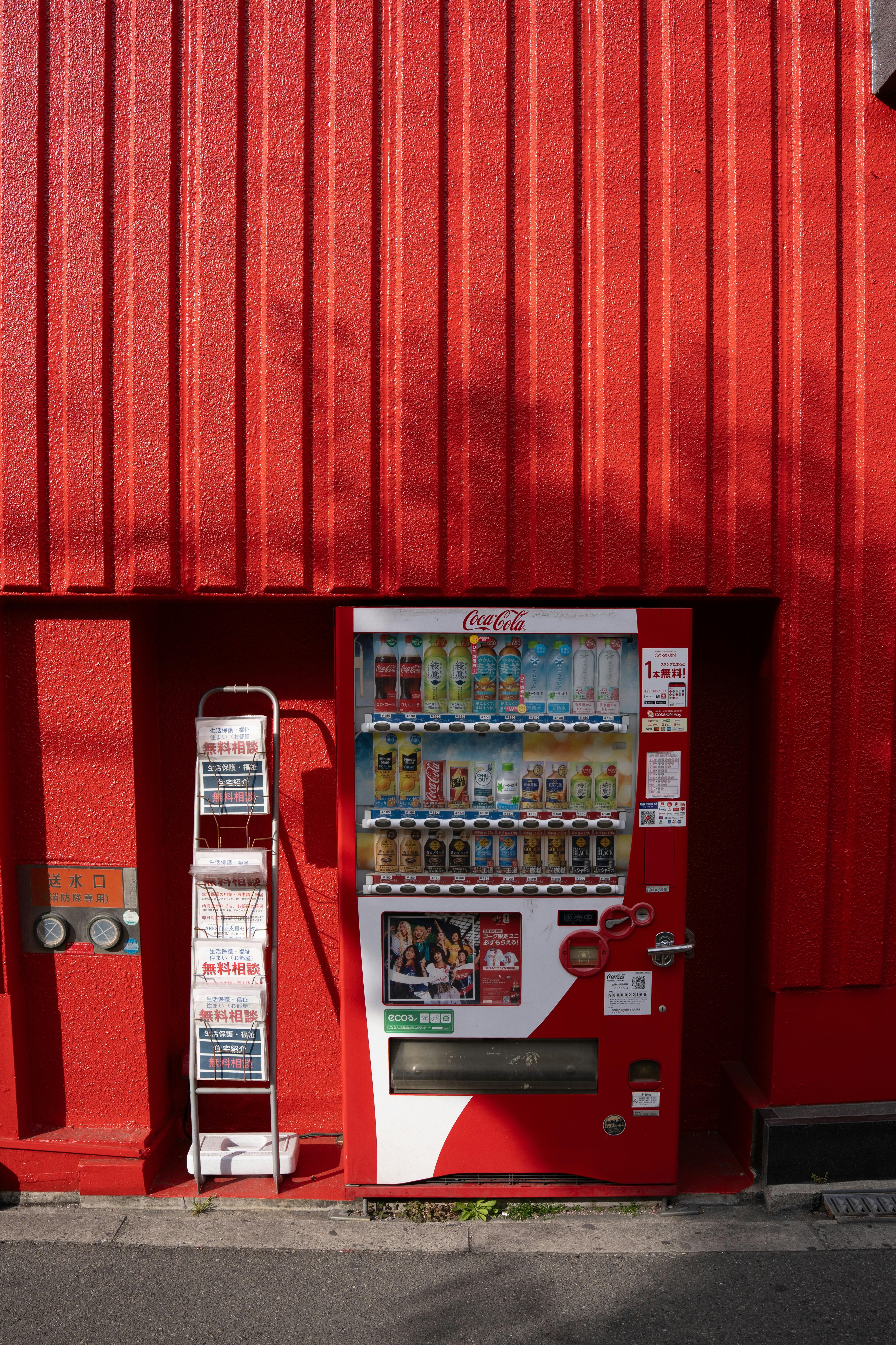 A red coca-cola vending machine against a vibrant red wall.