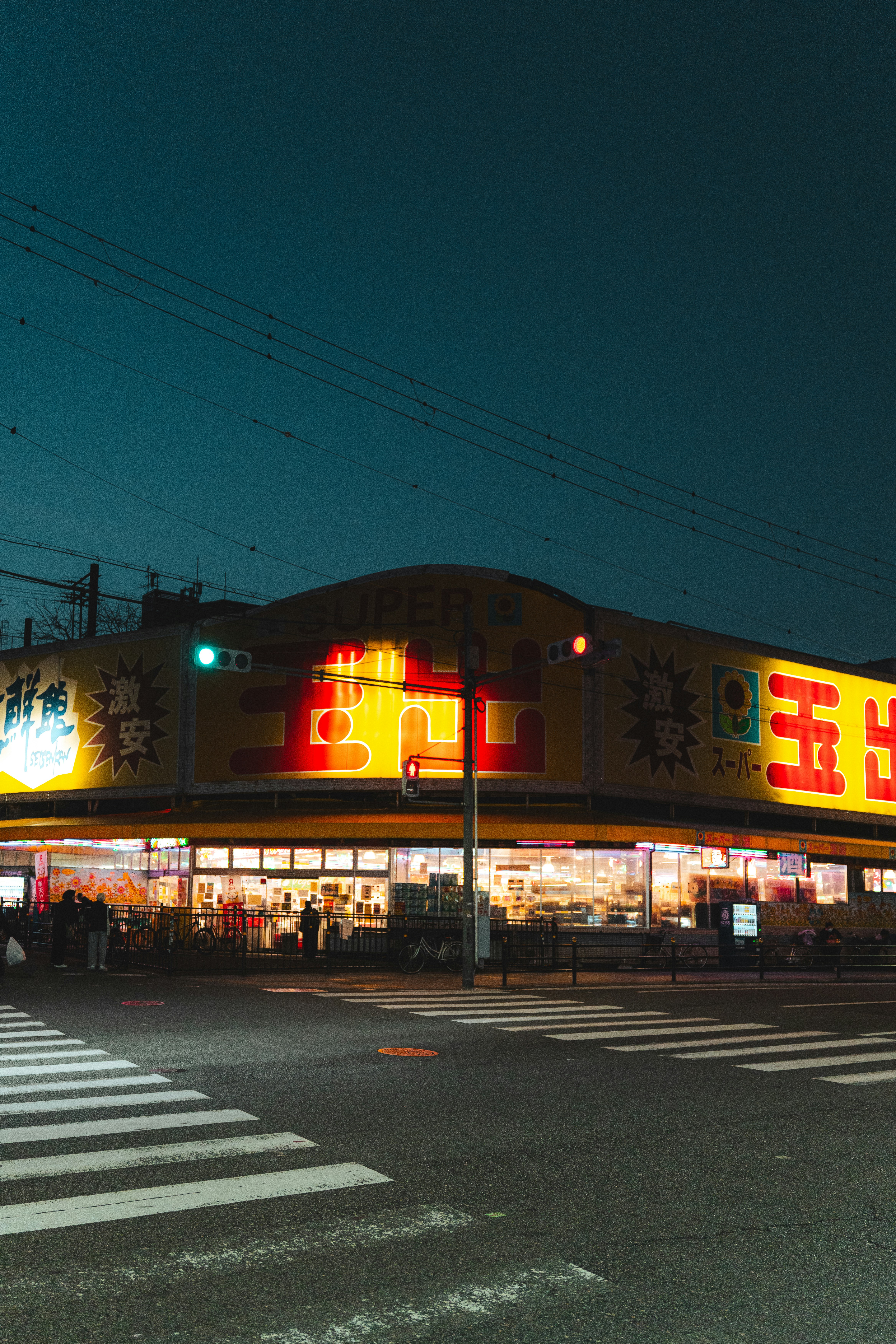 A brightly lit japanese store at night with a crosswalk.