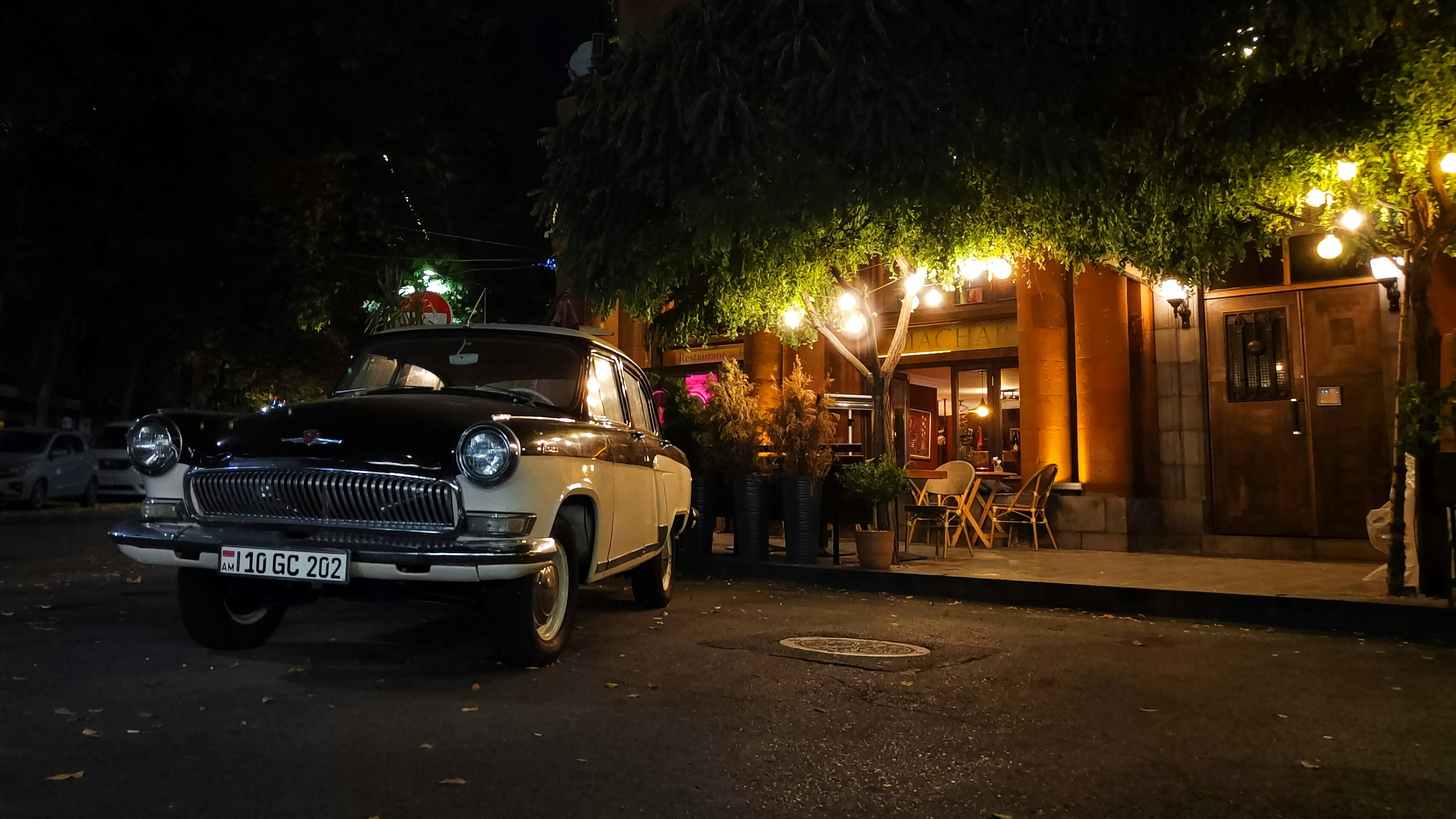A vintage car parked outside a cafe at night.