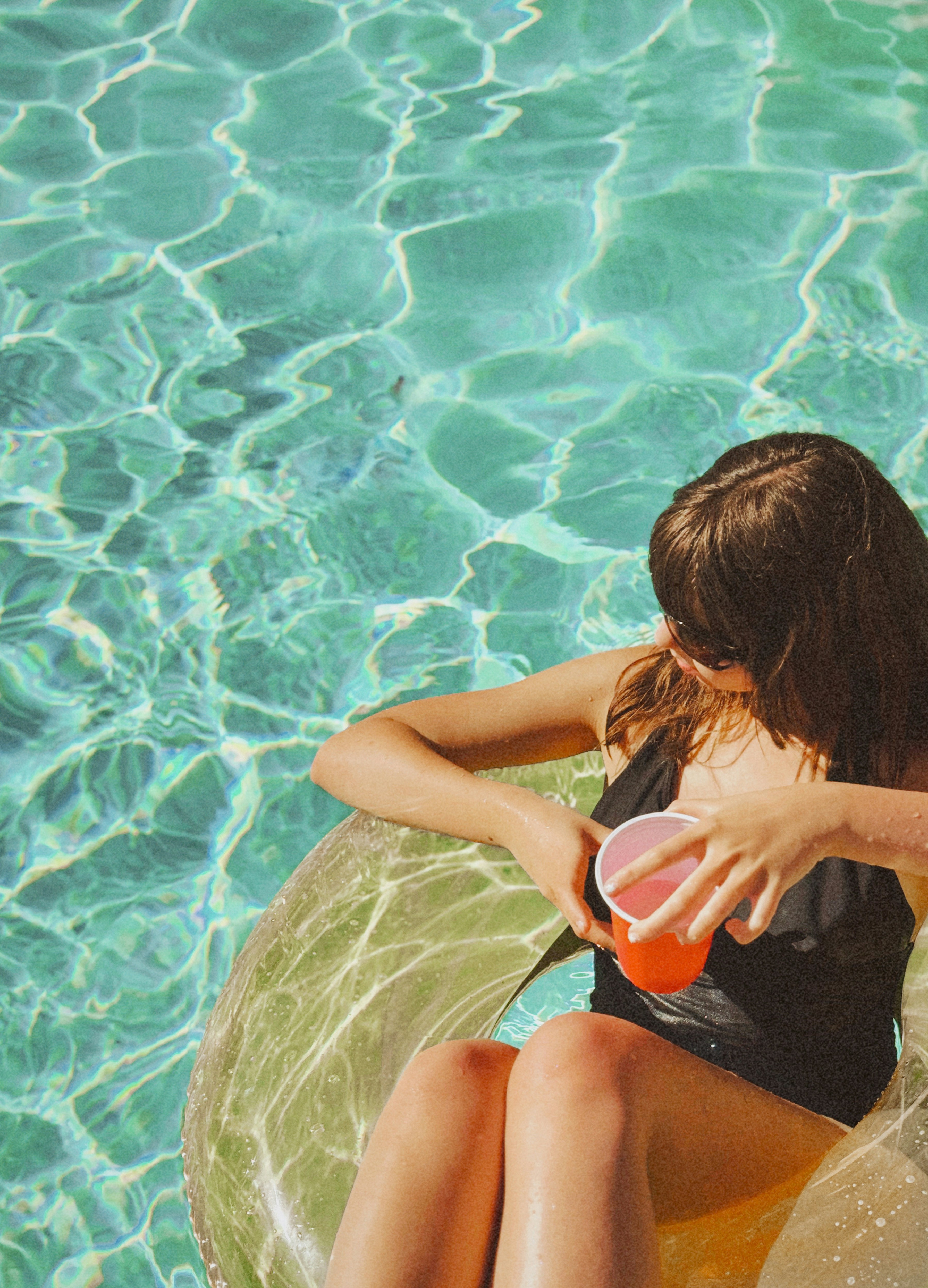 Woman on pool float holding orange cup