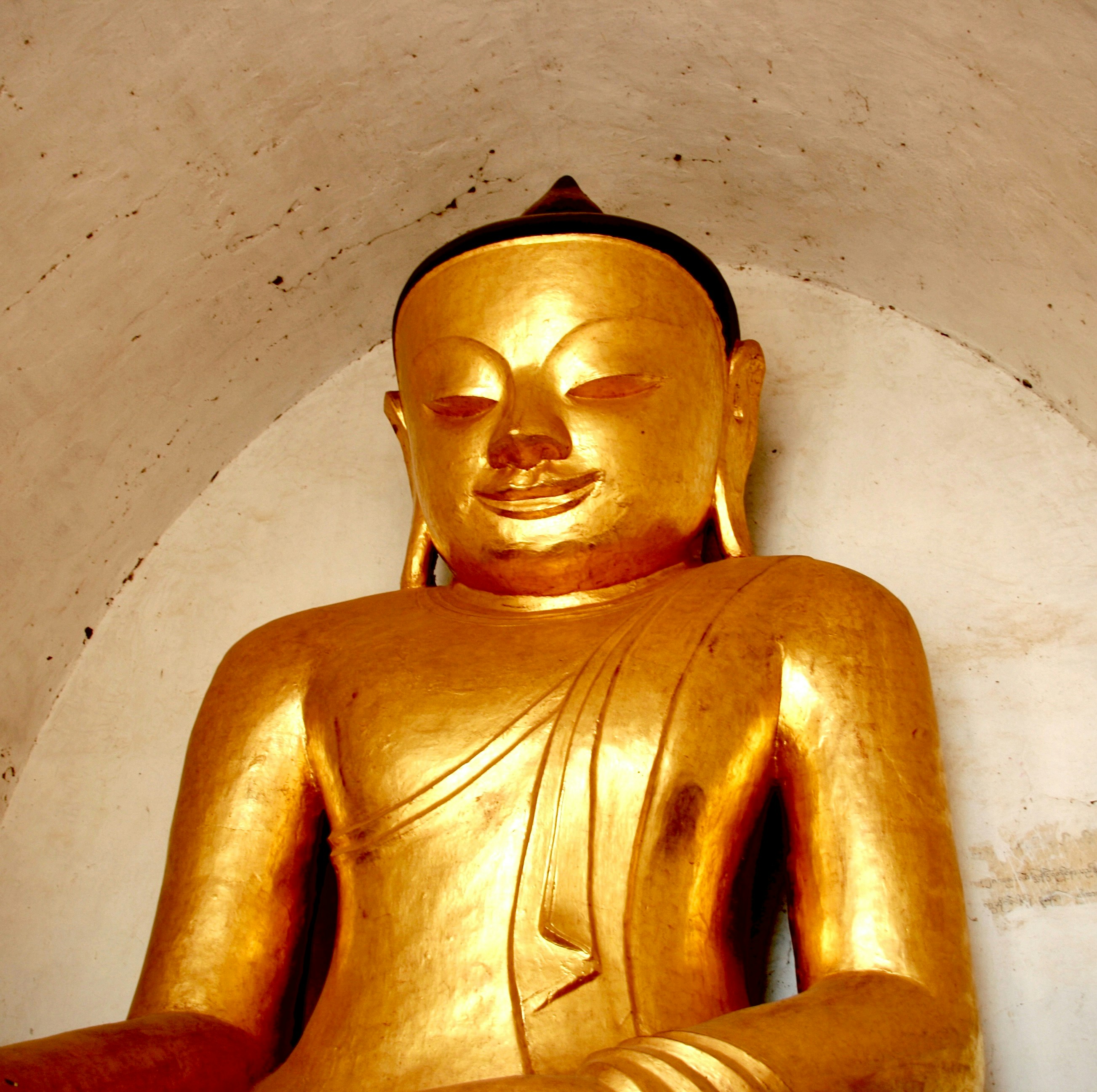 Une statue de Bouddha doré les yeux fermés.