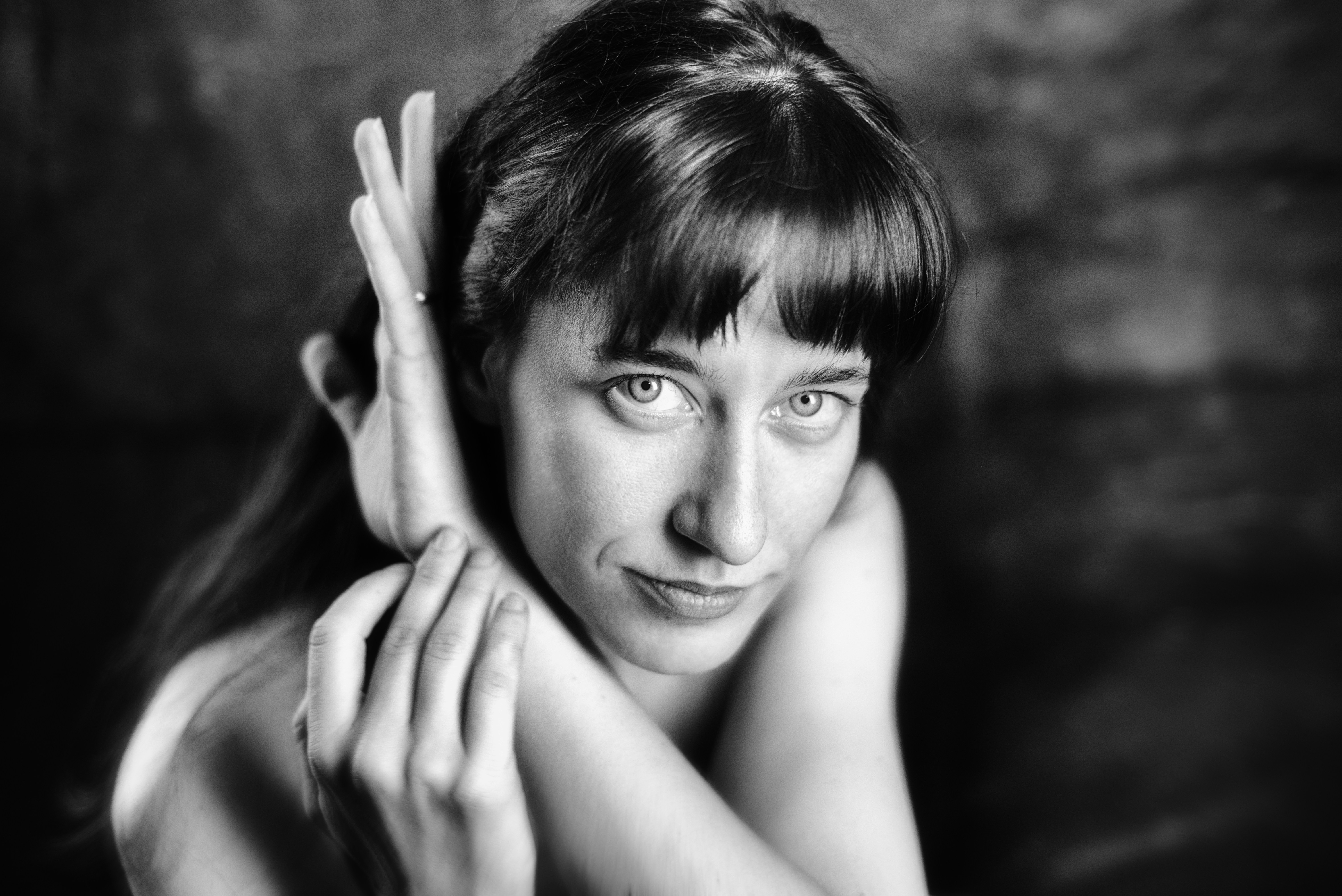 Woman with arms crossed looking intently in black and white.