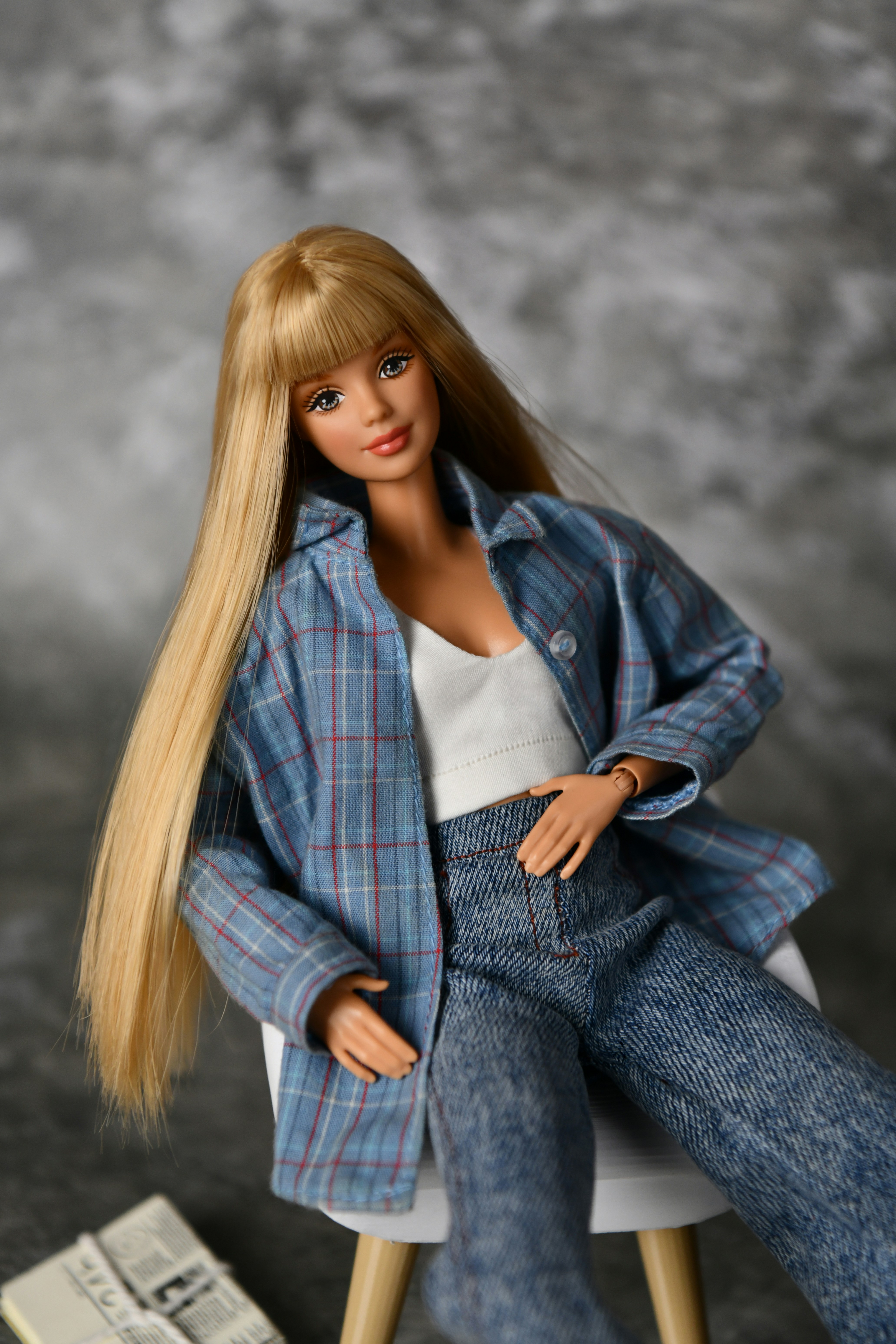 Poupée Barbie blonde portant une chemise à carreaux et un pantalon bleu.
