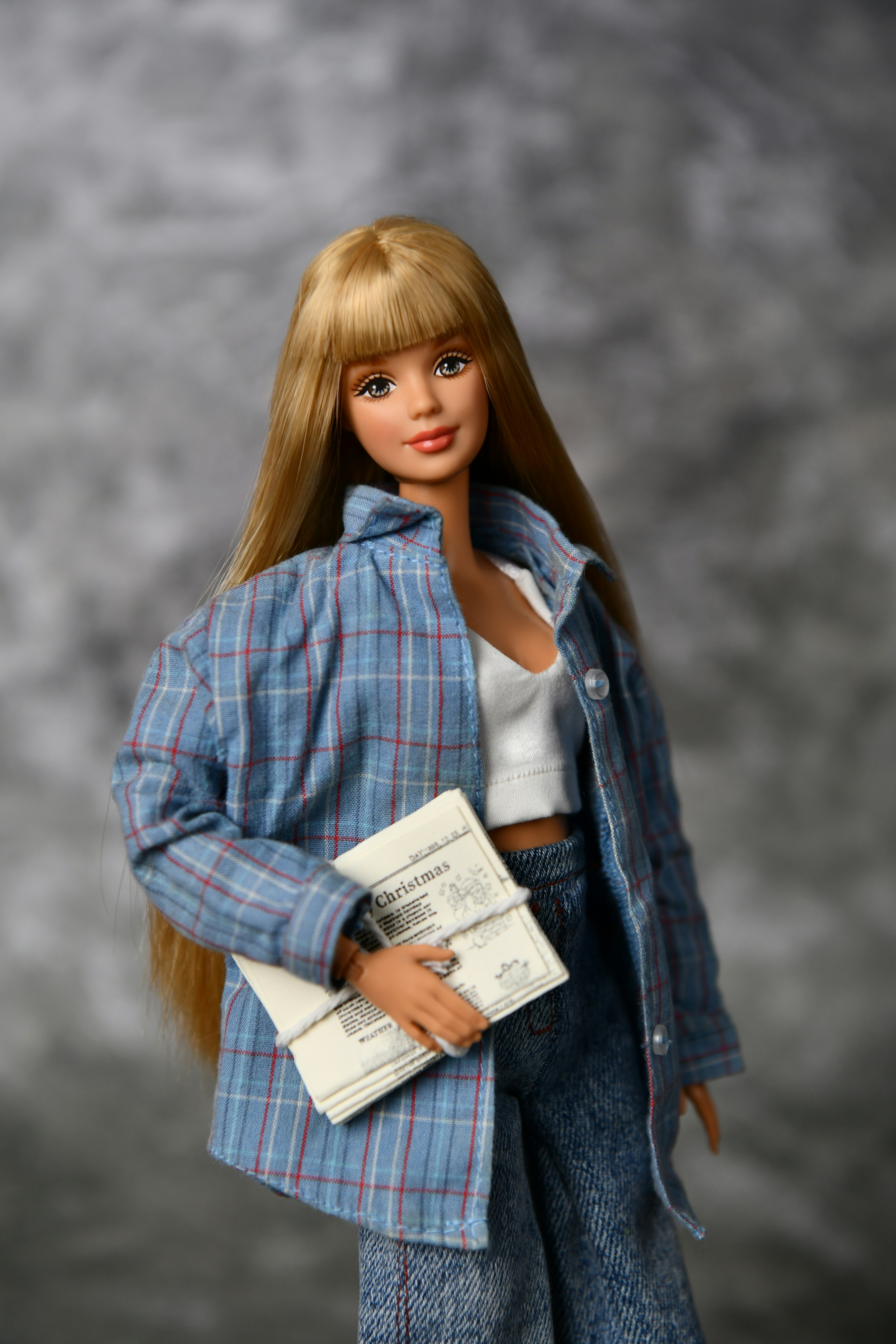 Une poupée blonde en chemise à carreaux tenant des papiers.