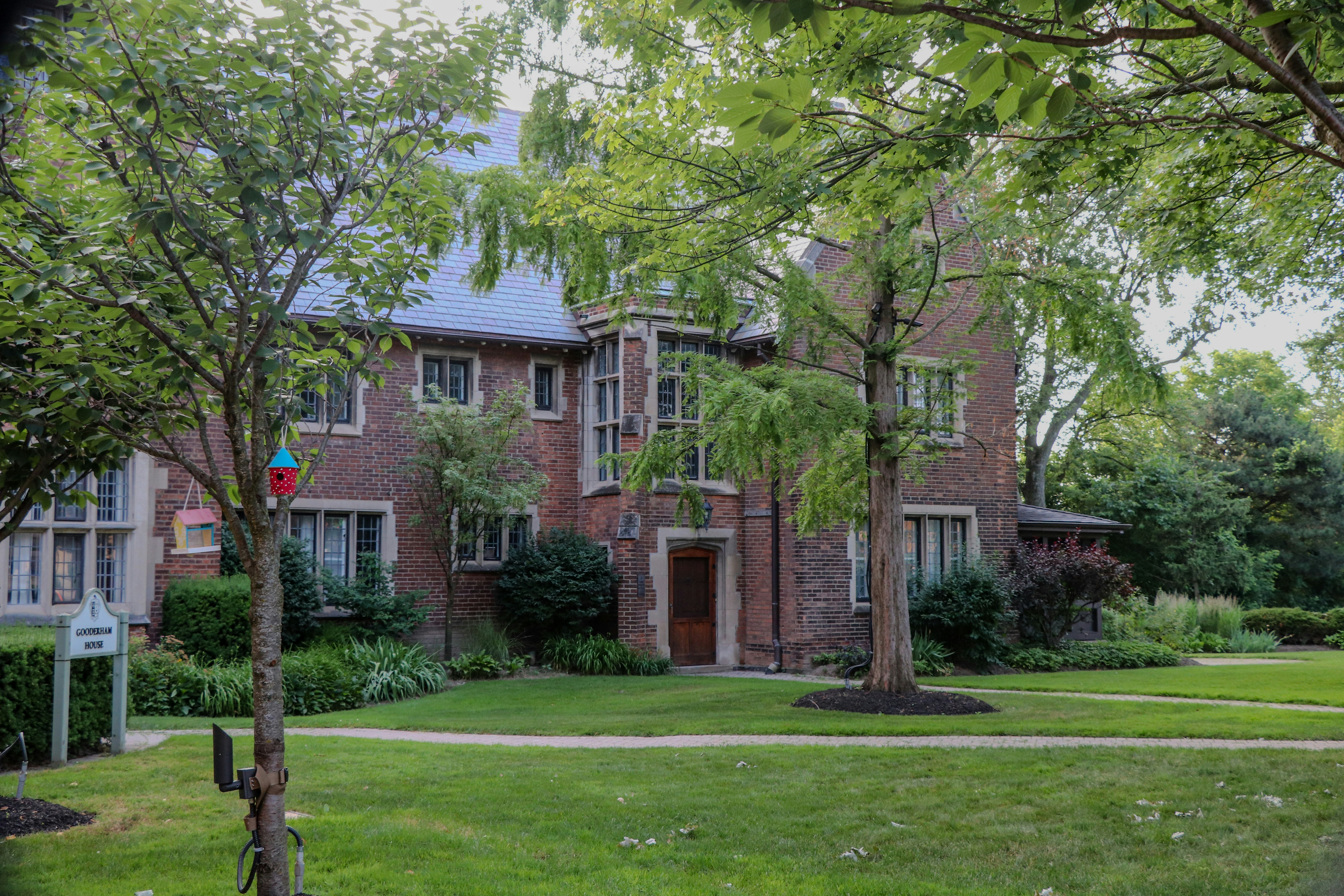 Historic brick mansion with green trees and a manicured lawn