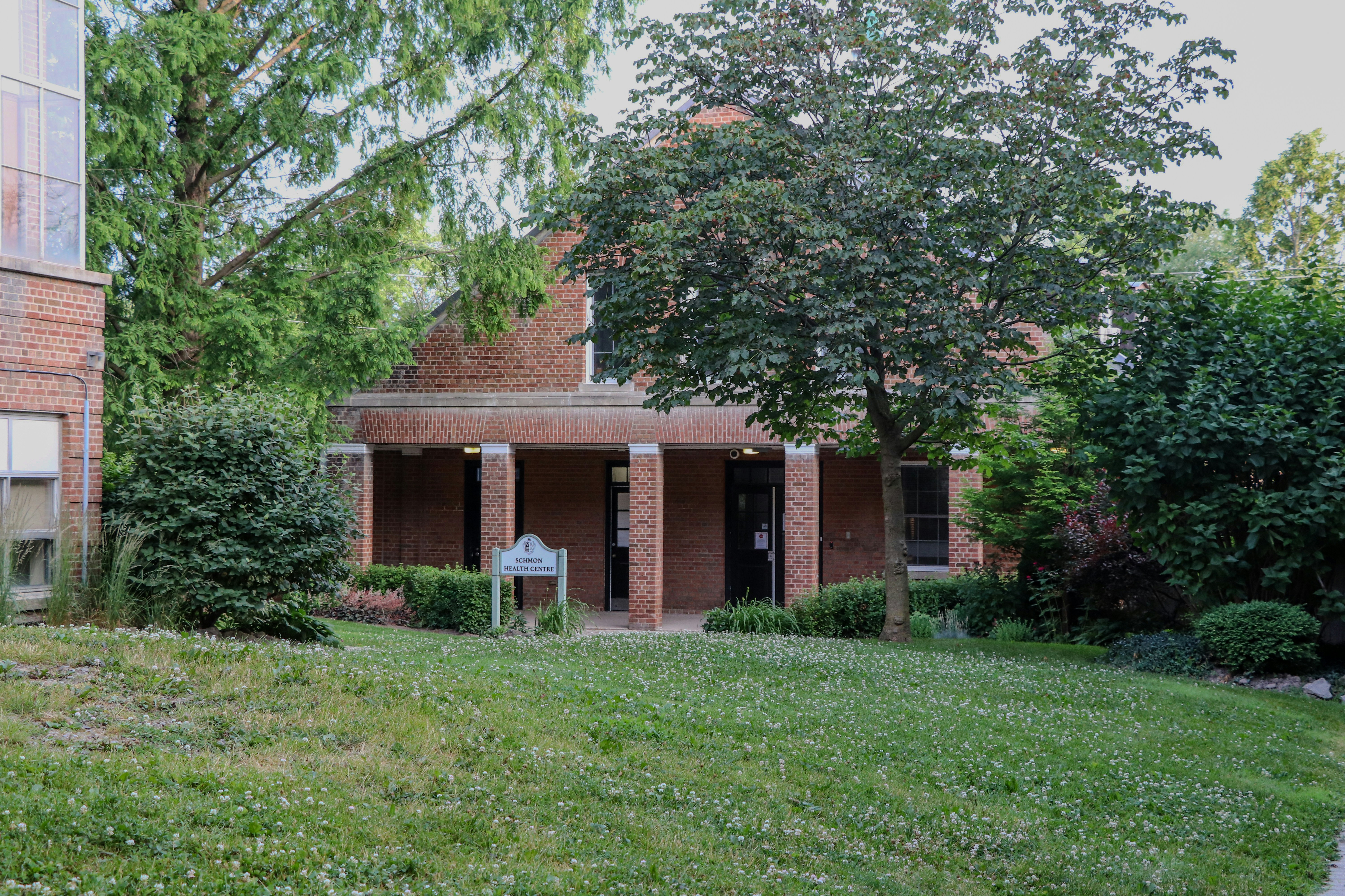 A brick building with a columned entrance and green lawn