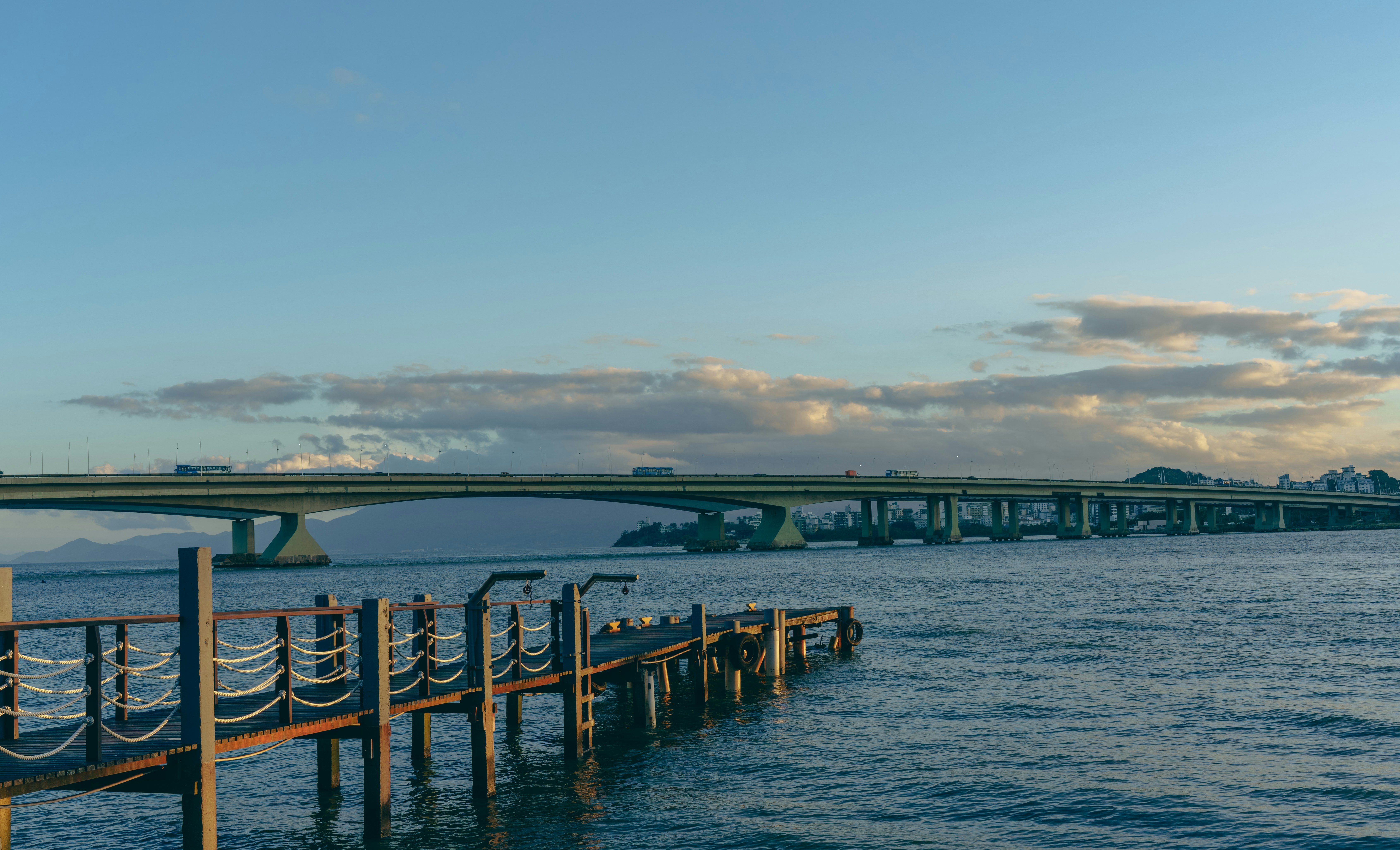 Old wooden pier in calm water with a bridge
