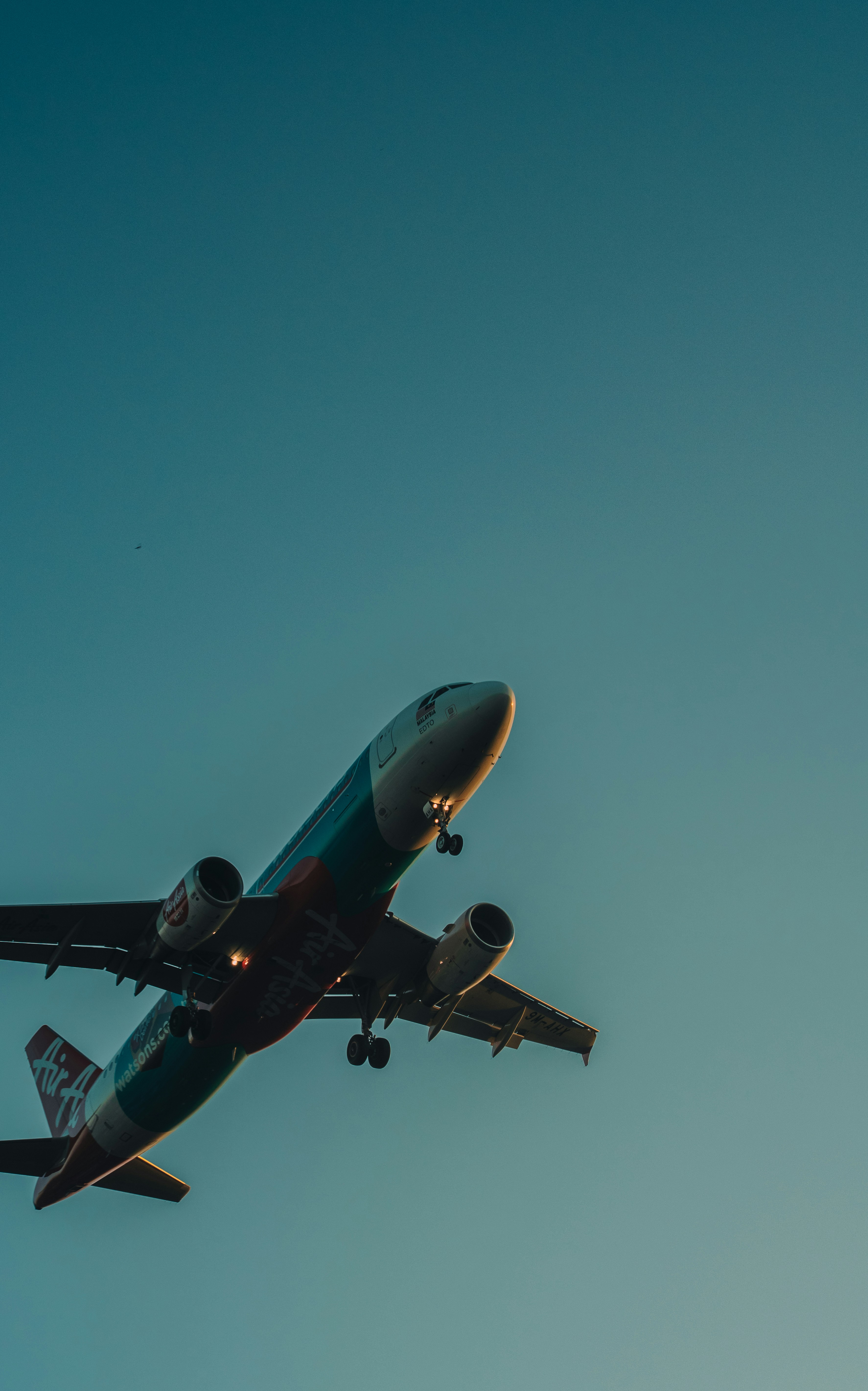 Avião comercial com trem de pouso abaixado contra um céu azul.
