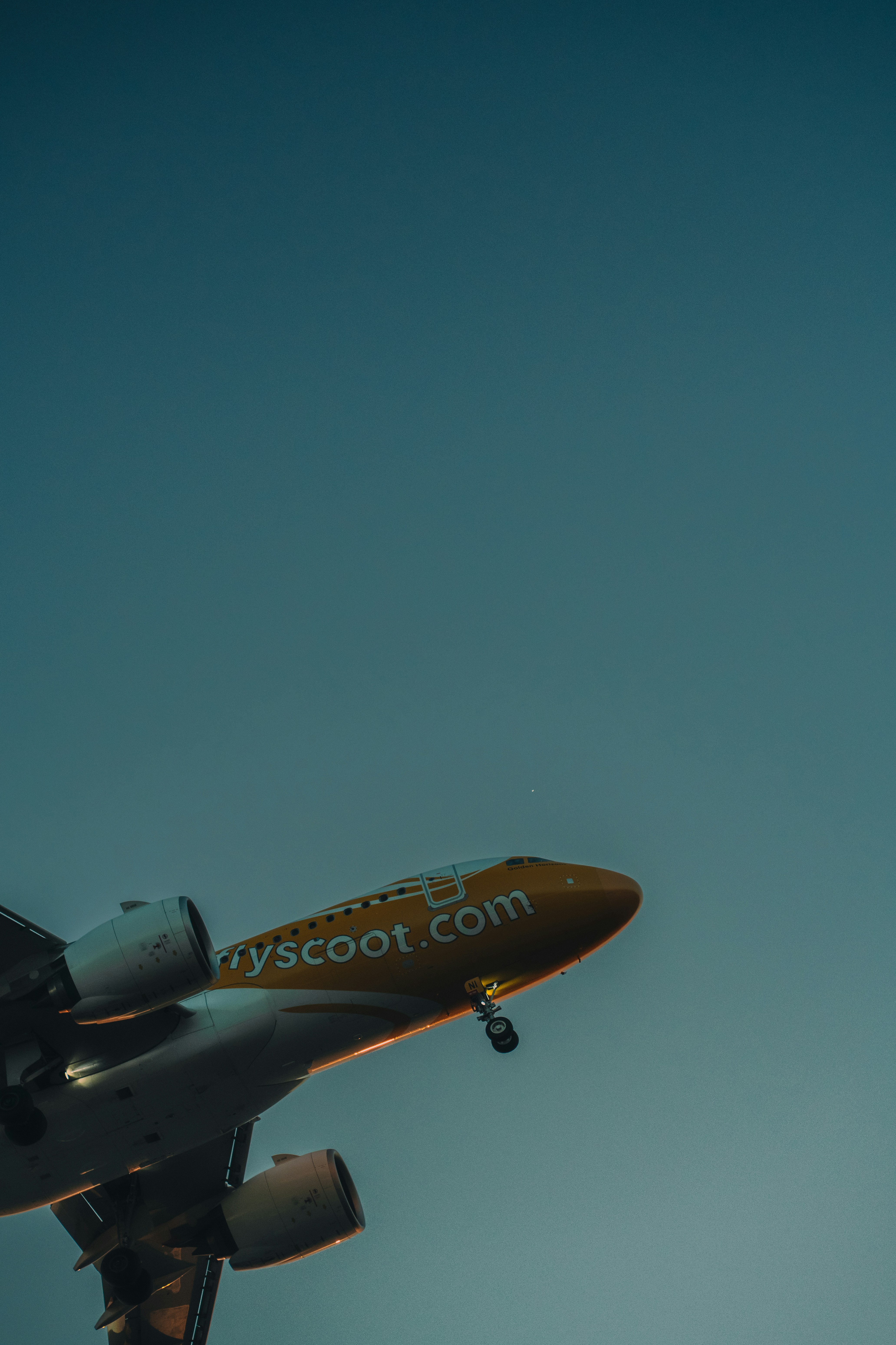 Avião laranja subindo para um céu azul claro.