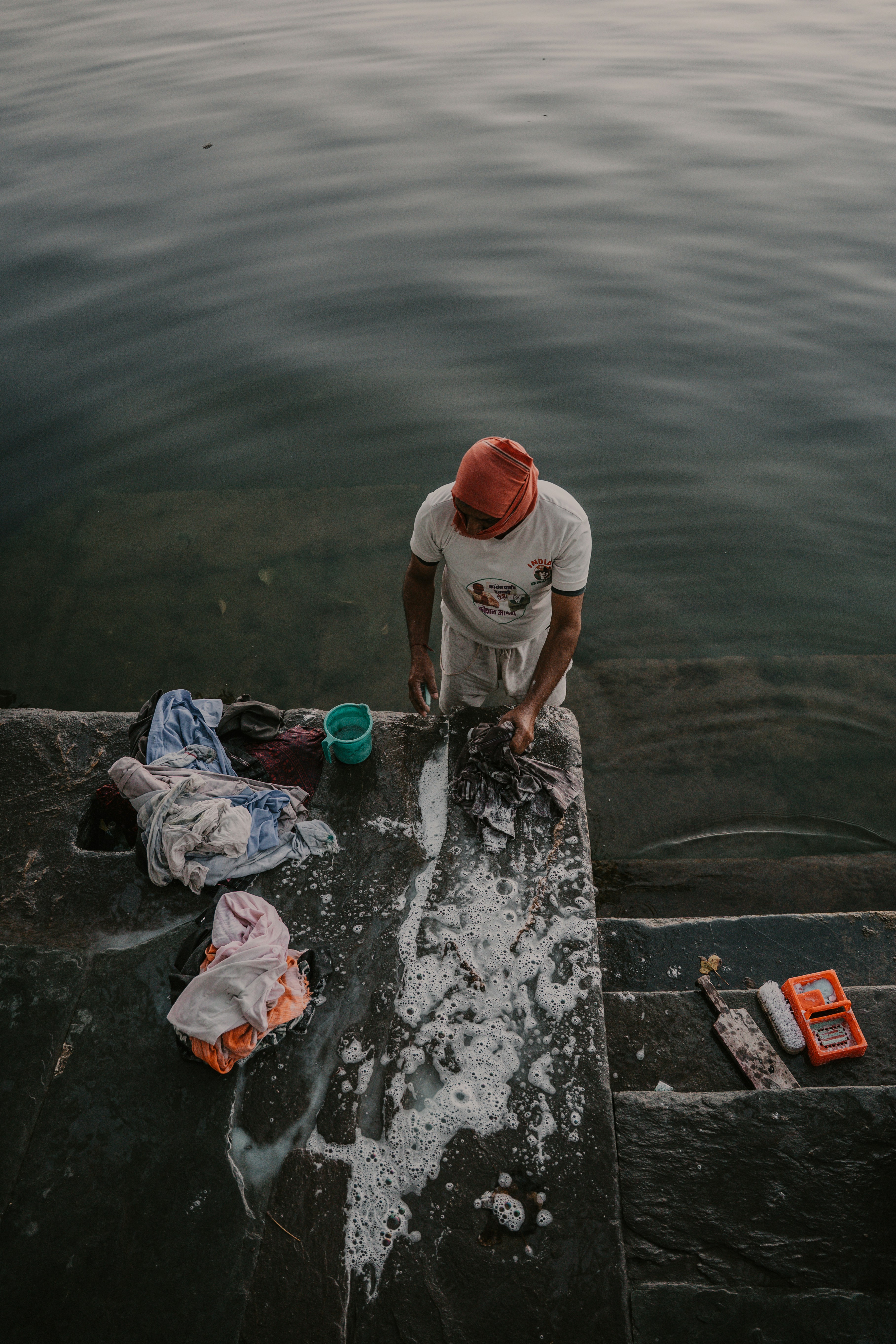 Person washing clothes by hand on stone steps.