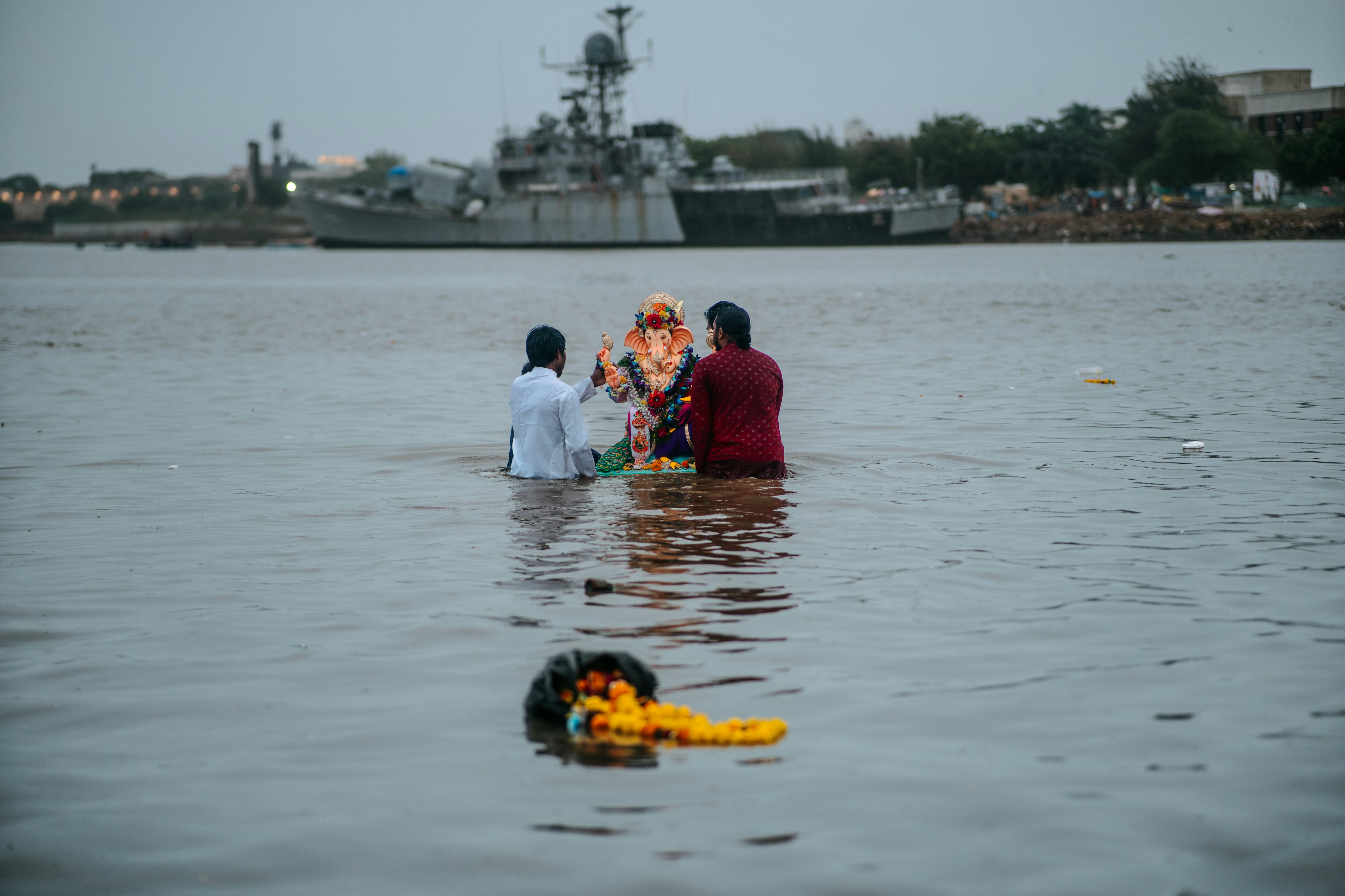 二人が船の近くの水にガネーシャ像を浸します