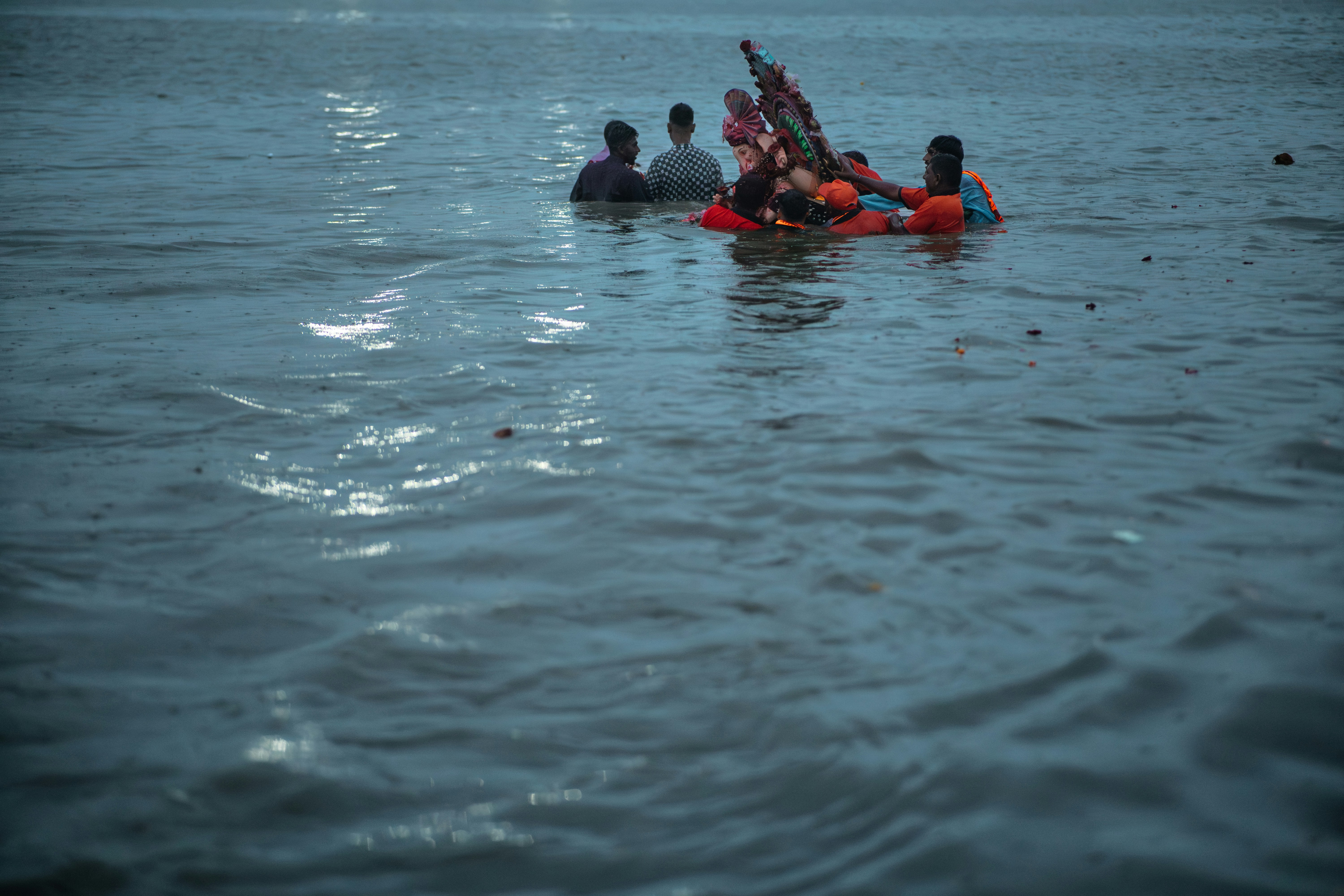 People immerse a decorated idol in dark water.
