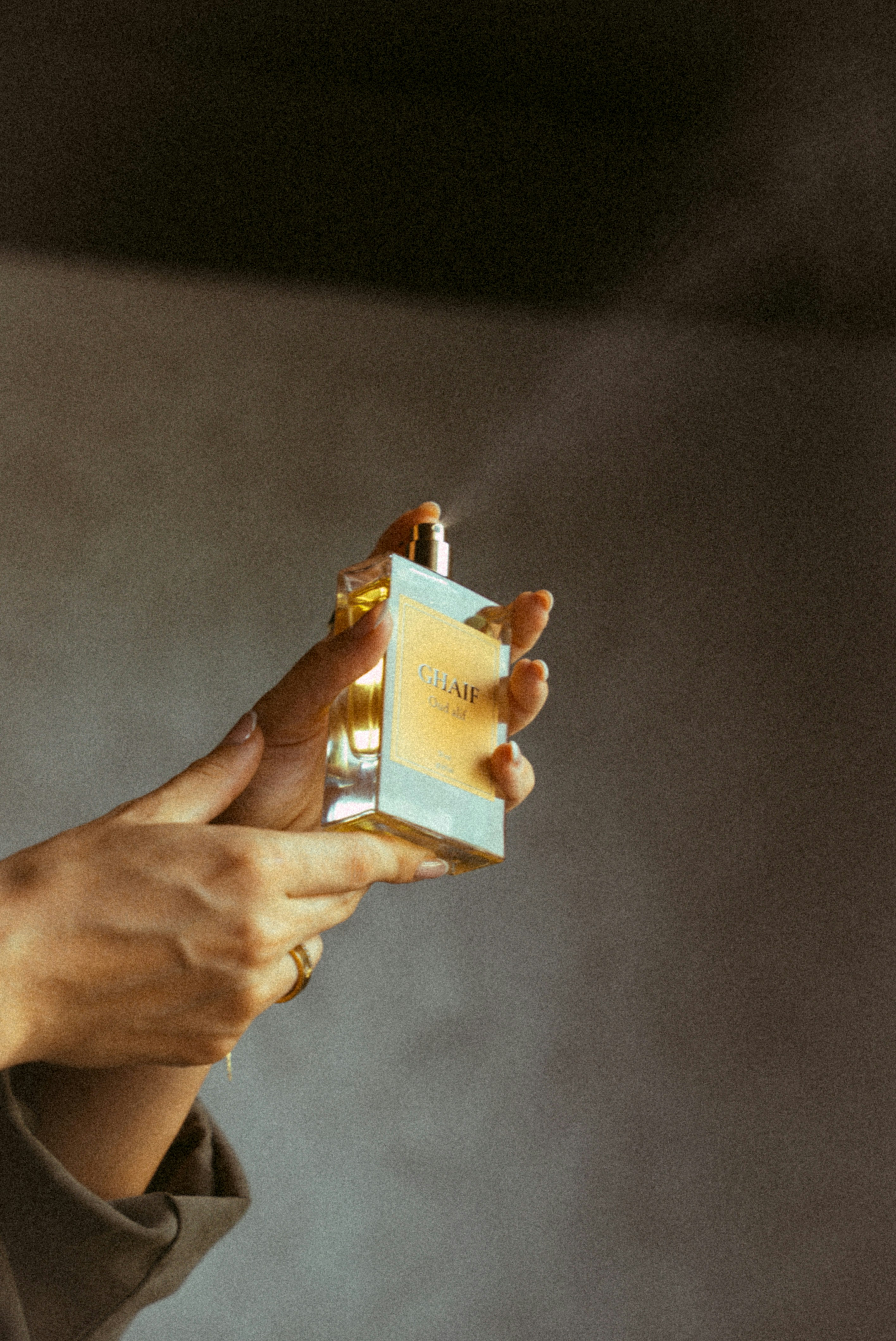 Mãos borrifando perfume de um frasco