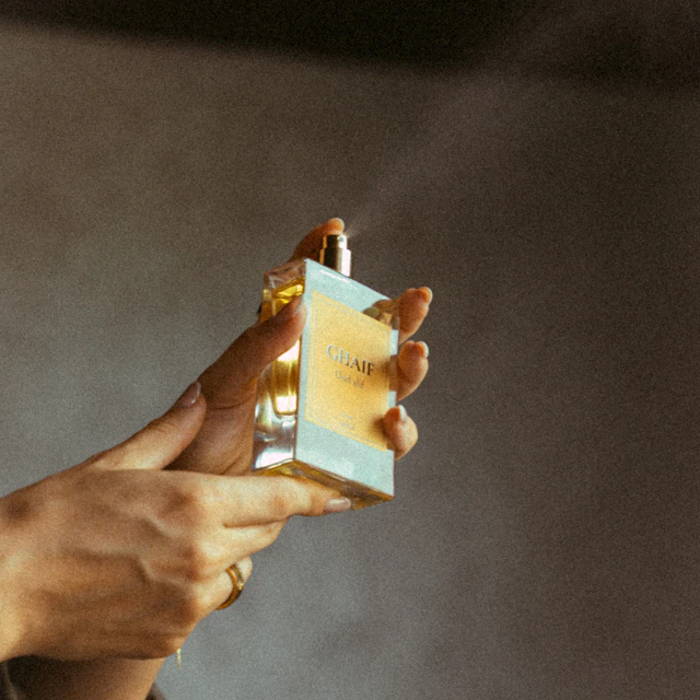 Hands spraying perfume from a glass bottle