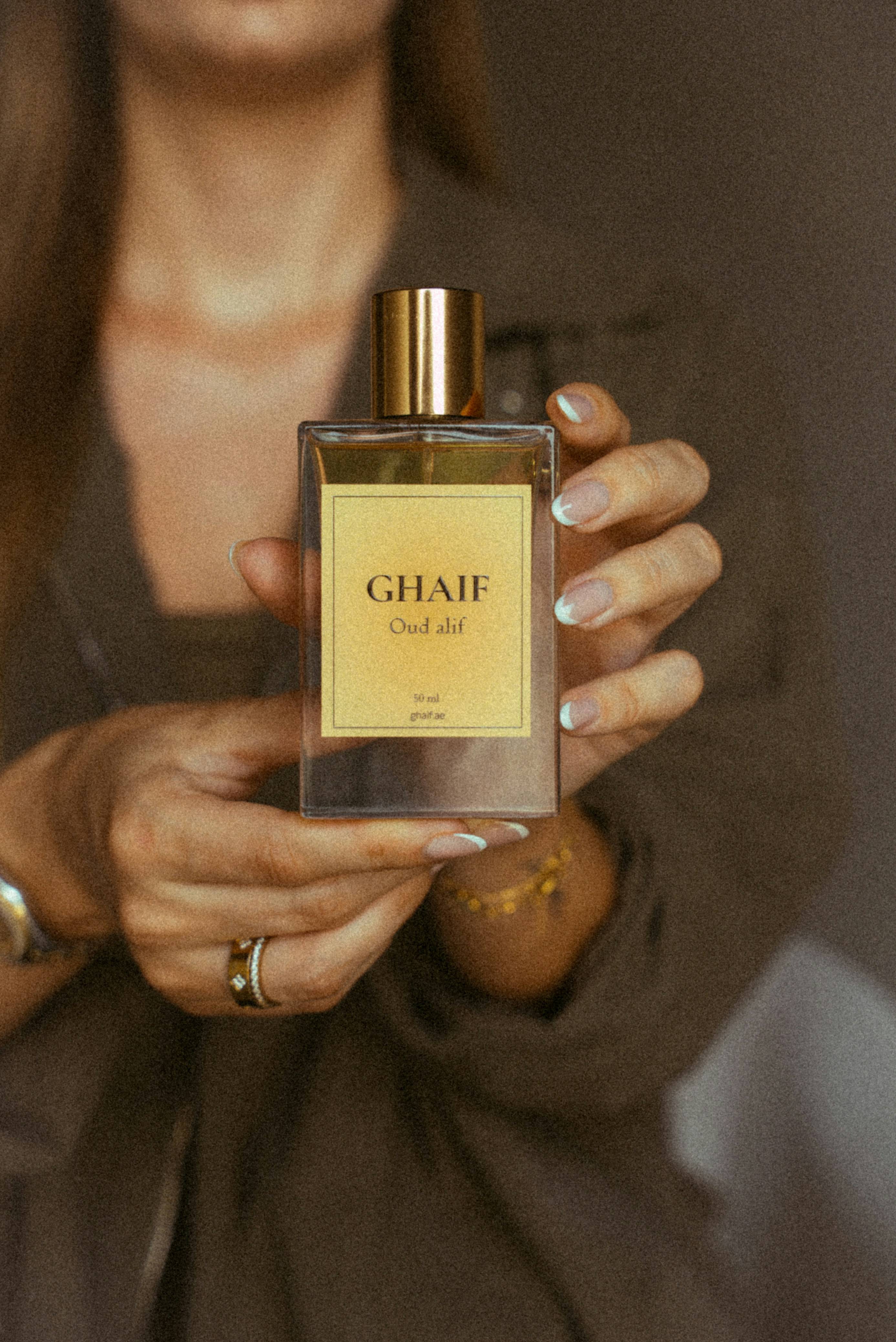 Mãos segurando o frasco de perfume ghaif oud alif