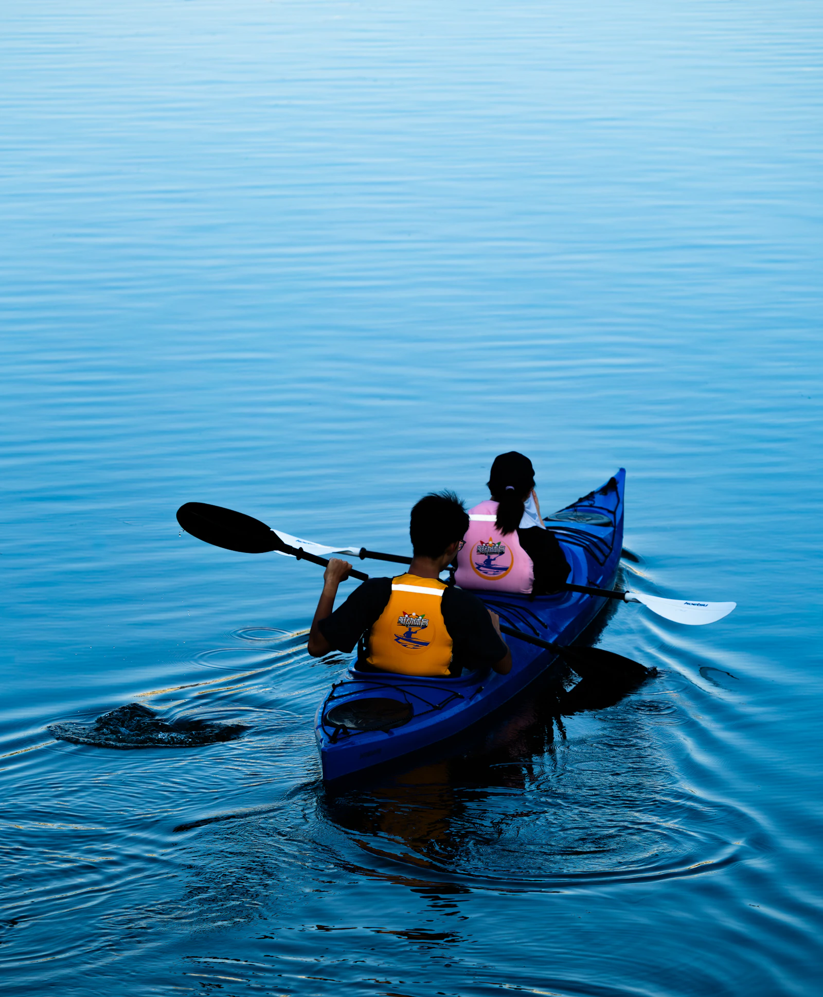 Kayakers wearing life vests while paddling together on calm water