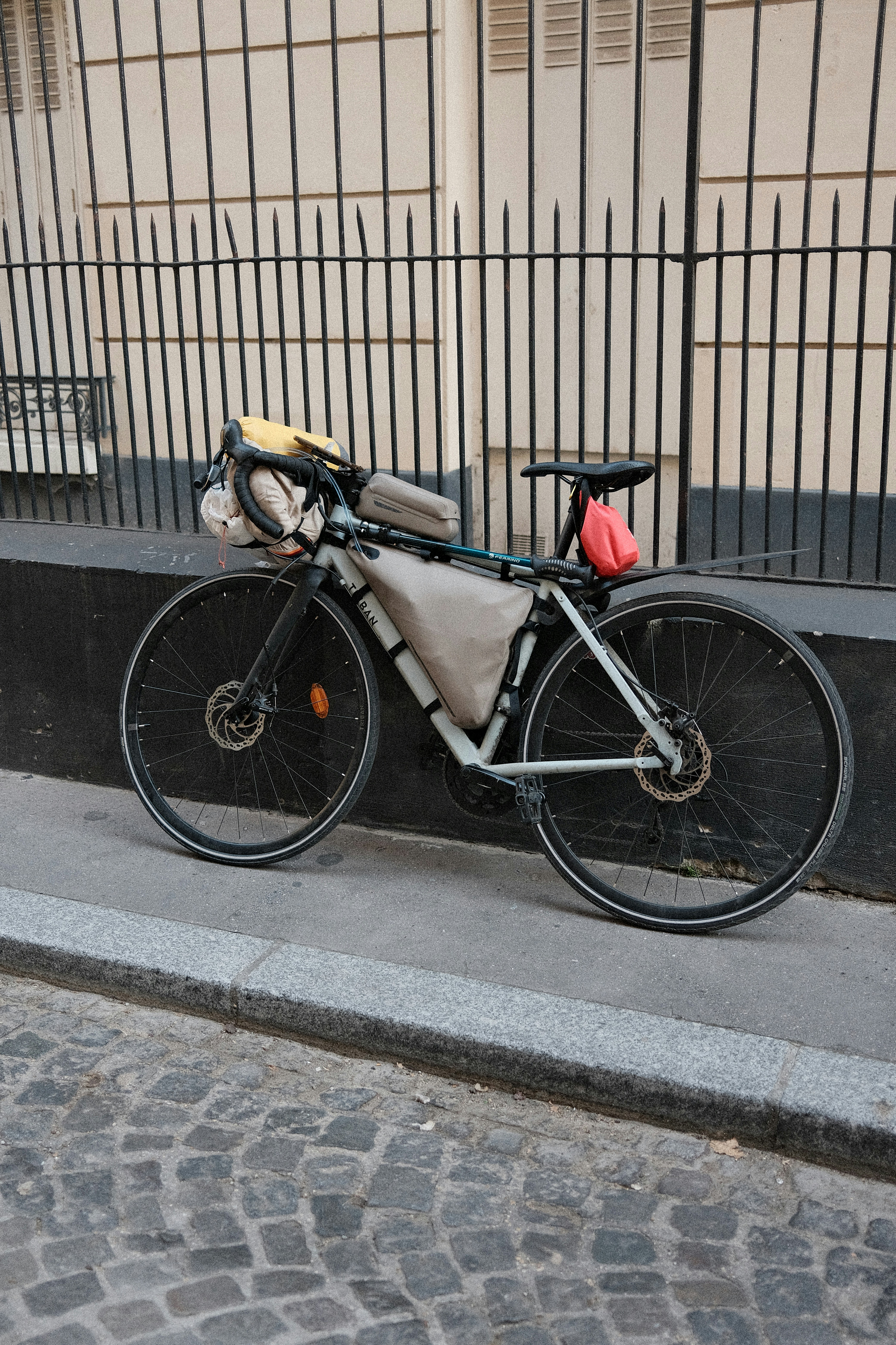 A touring bicycle with bags parked against a metal fence