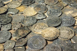 Numerous old, tarnished metal coins piled together