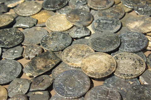 Numerous old, tarnished metal coins piled together