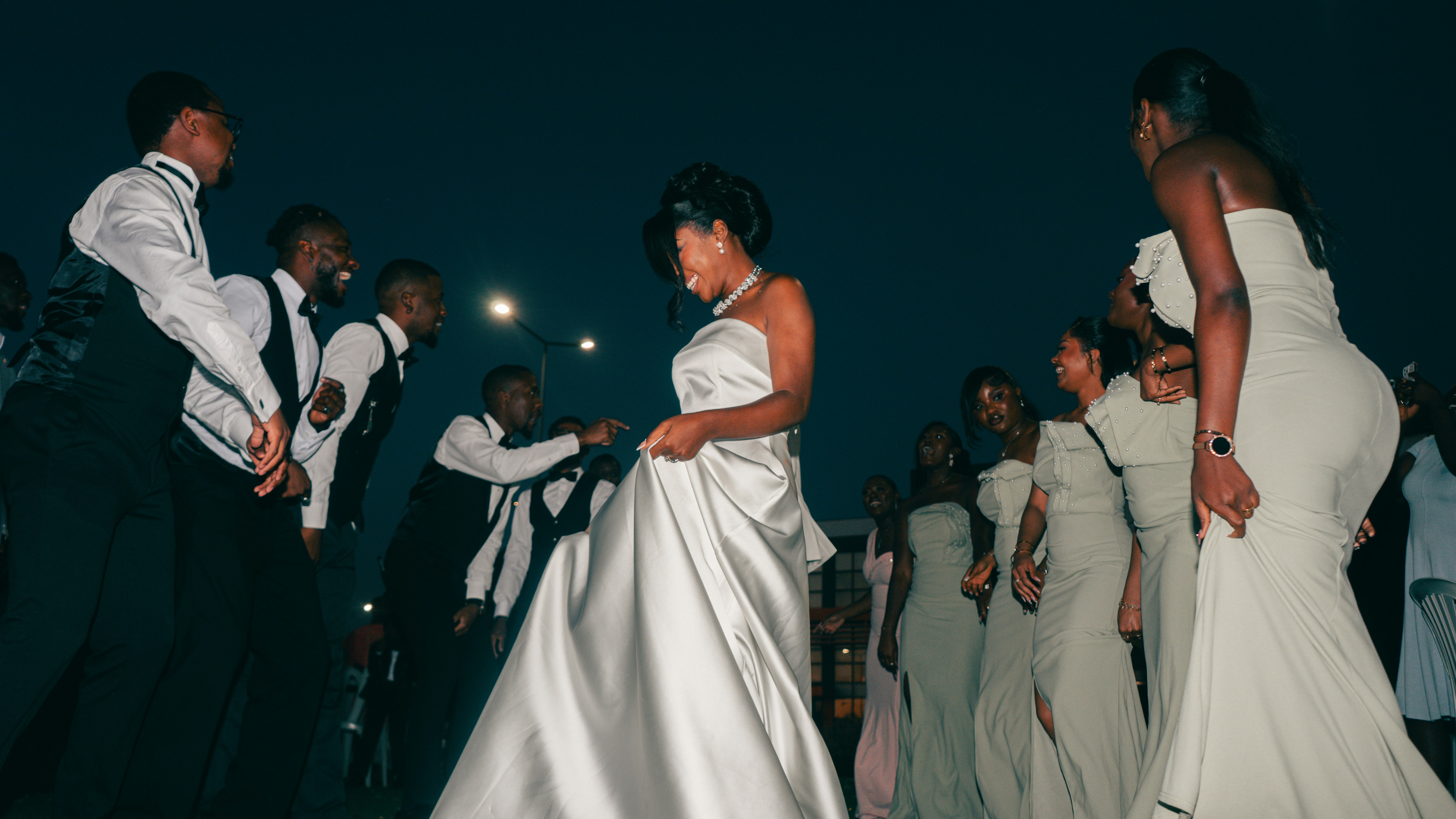 Bride dancing with guests under the night sky.