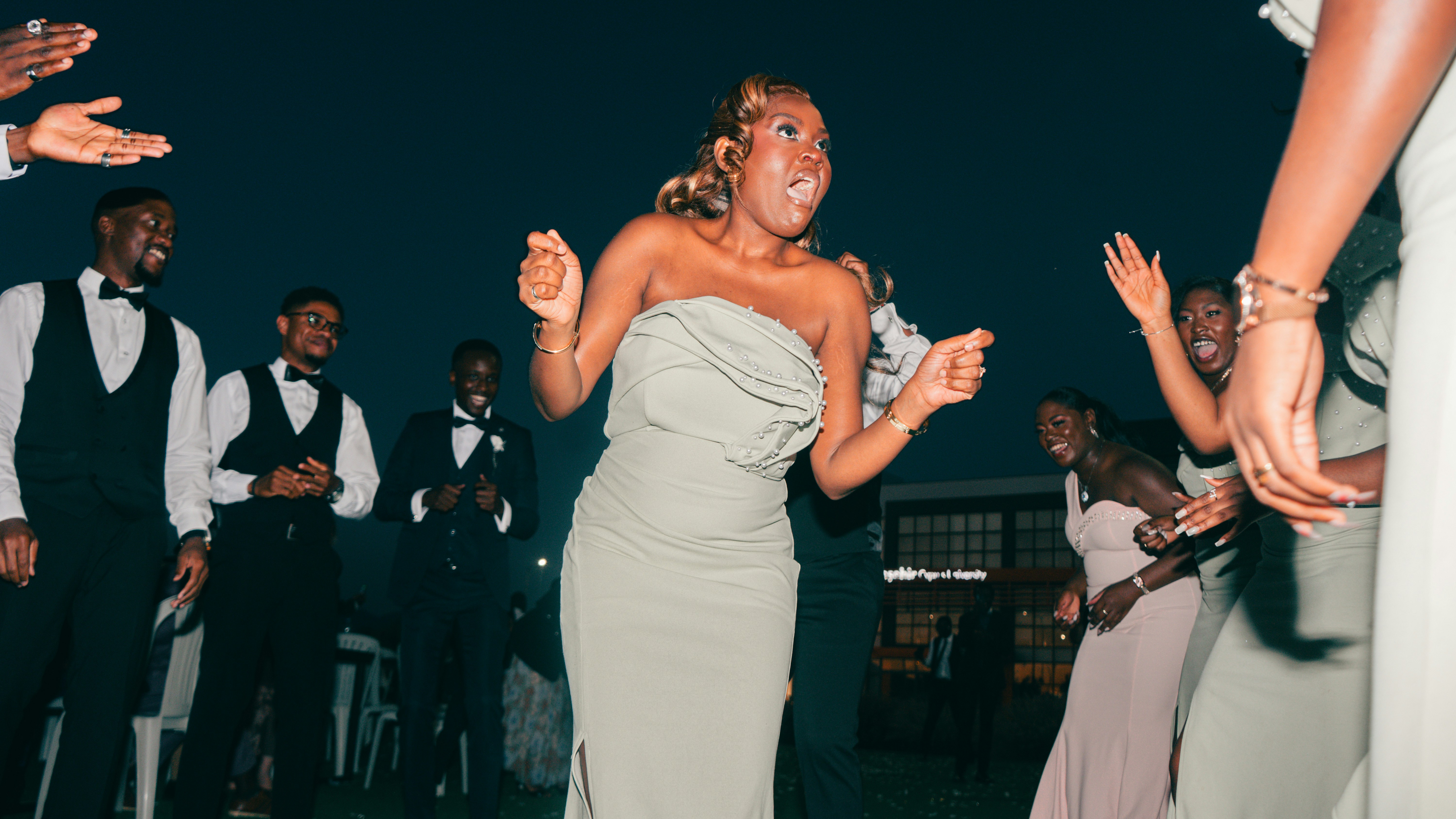 A young woman dancing energetically among formally dressed guests.